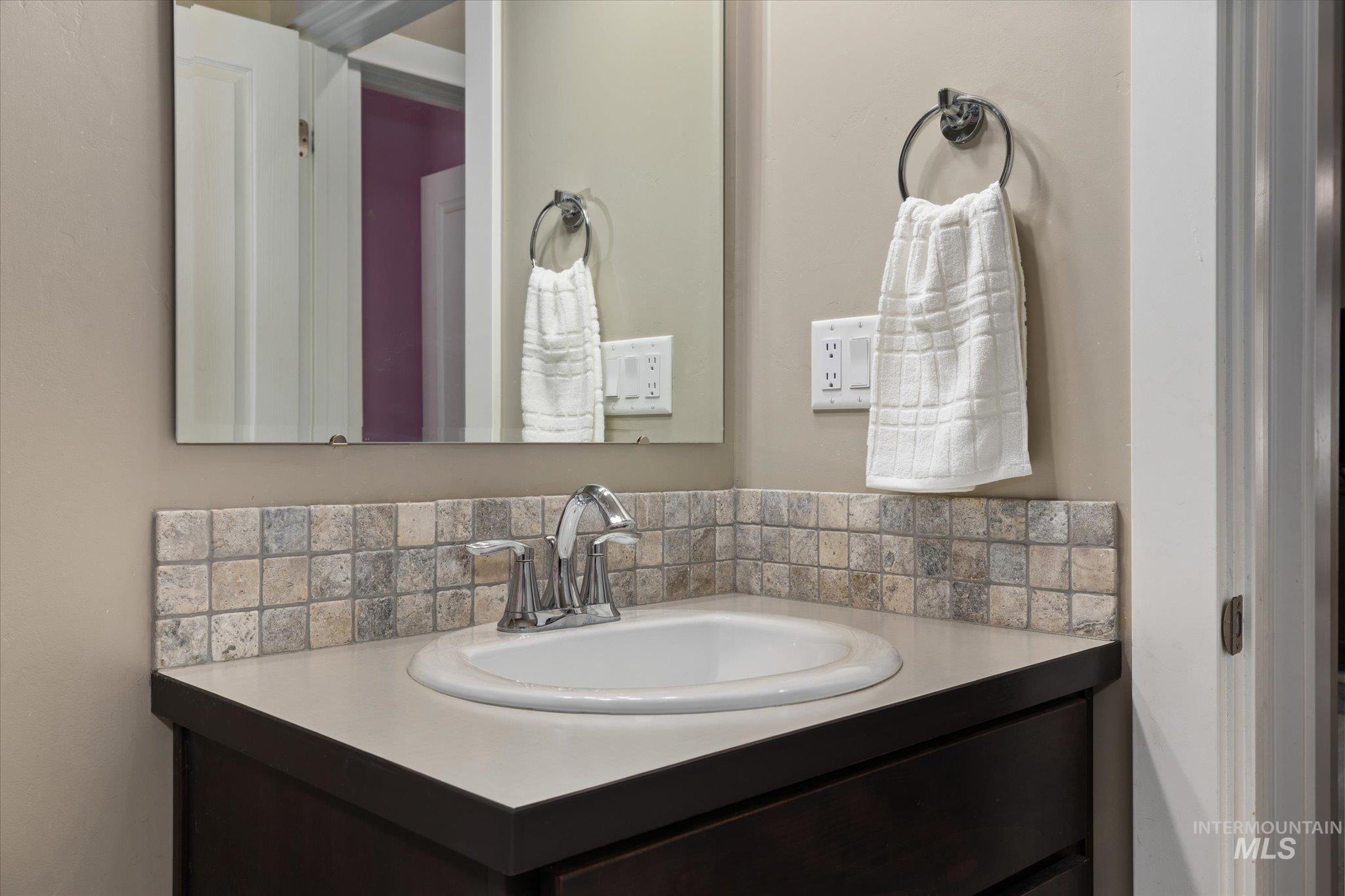 Bathroom featuring vanity and tasteful backsplash