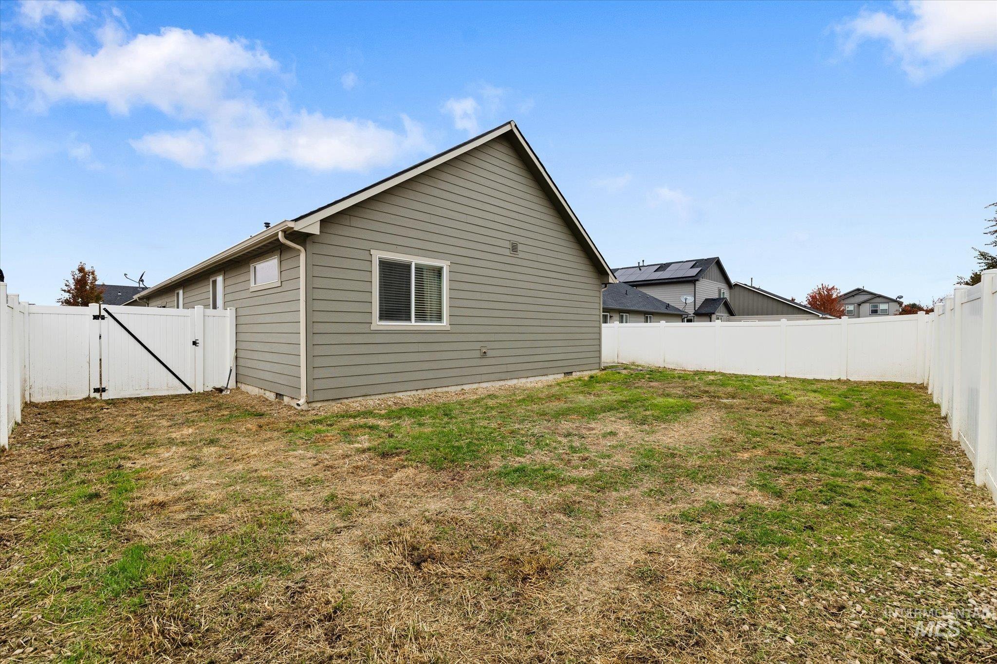 View of side of home with a fenced backyard and a gate