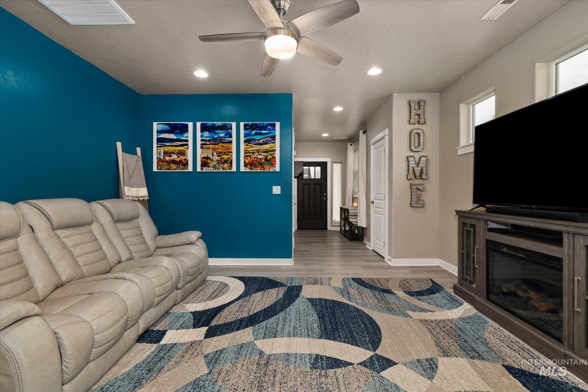 Living room featuring recessed lighting, wood finished floors, ceiling fan, and a glass covered fireplace
