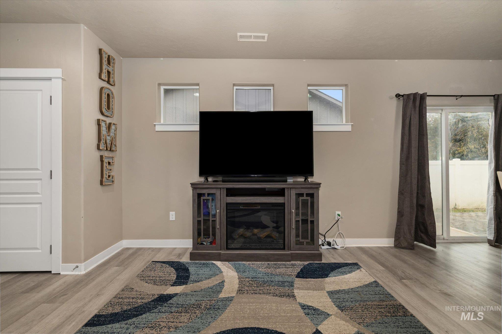 Living room with wood finished floors and a glass covered fireplace