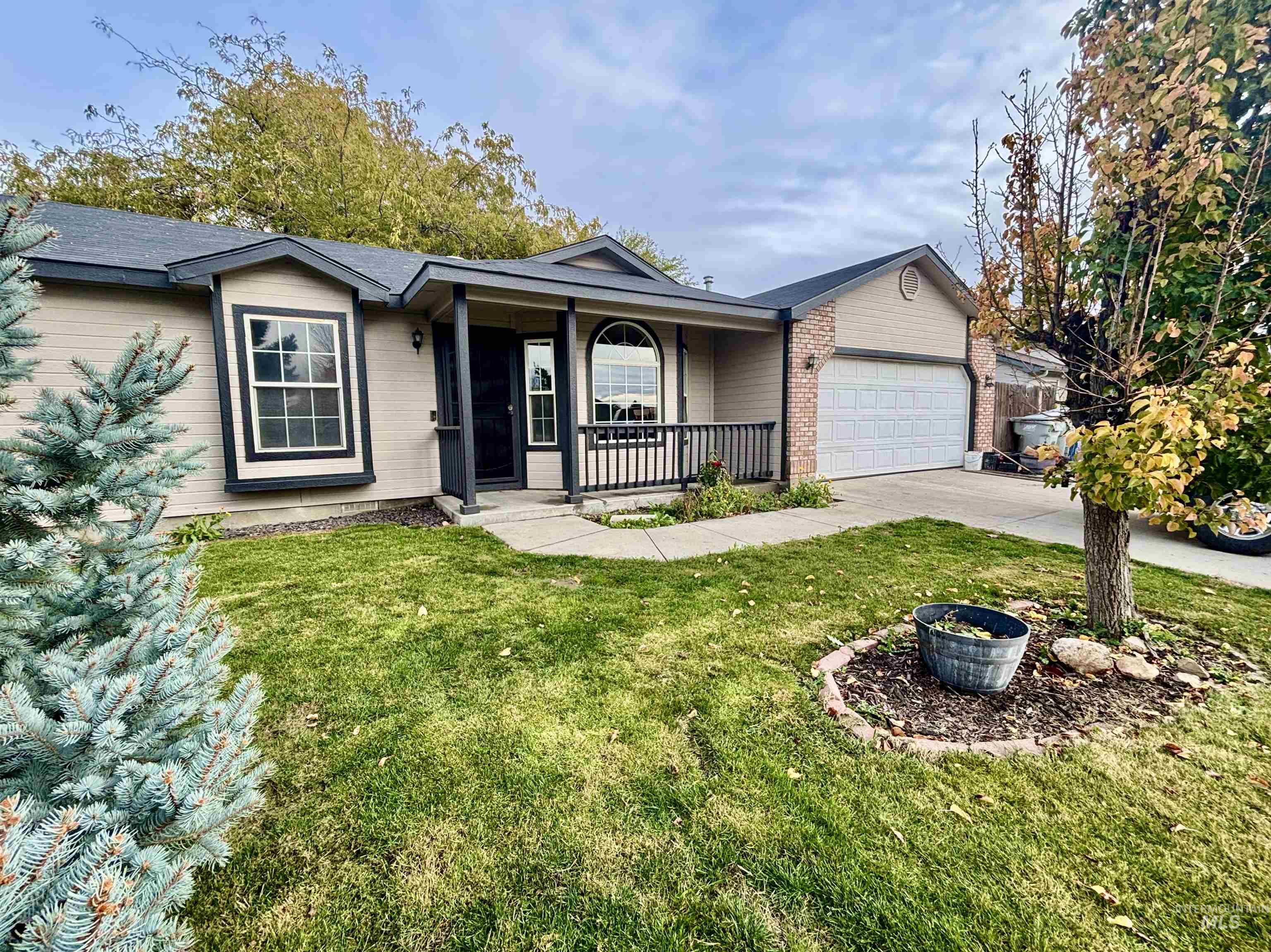 Single story home with covered porch, a front yard, driveway, a garage, and brick siding