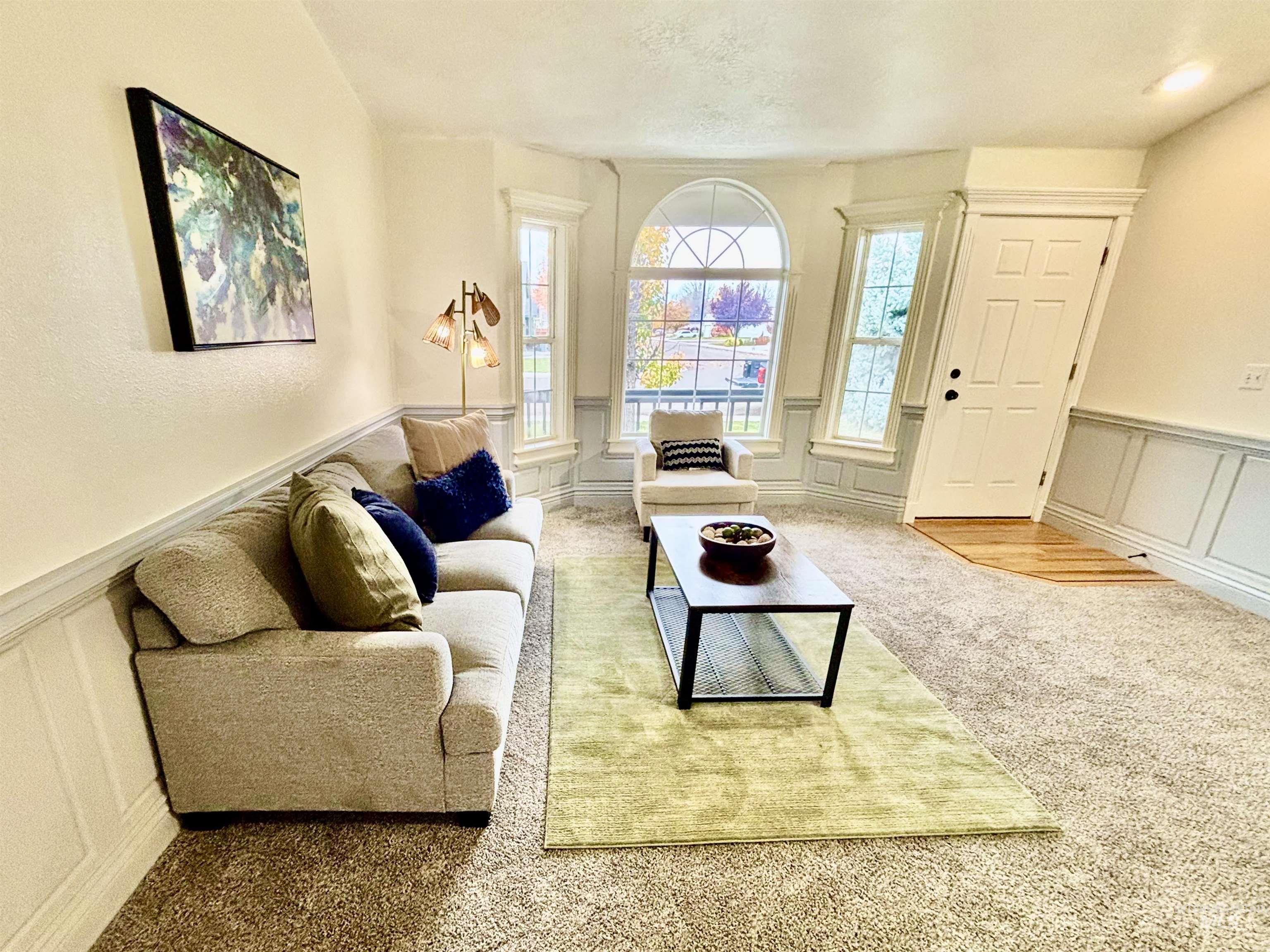 Carpeted living area with a decorative wall and a wainscoted wall