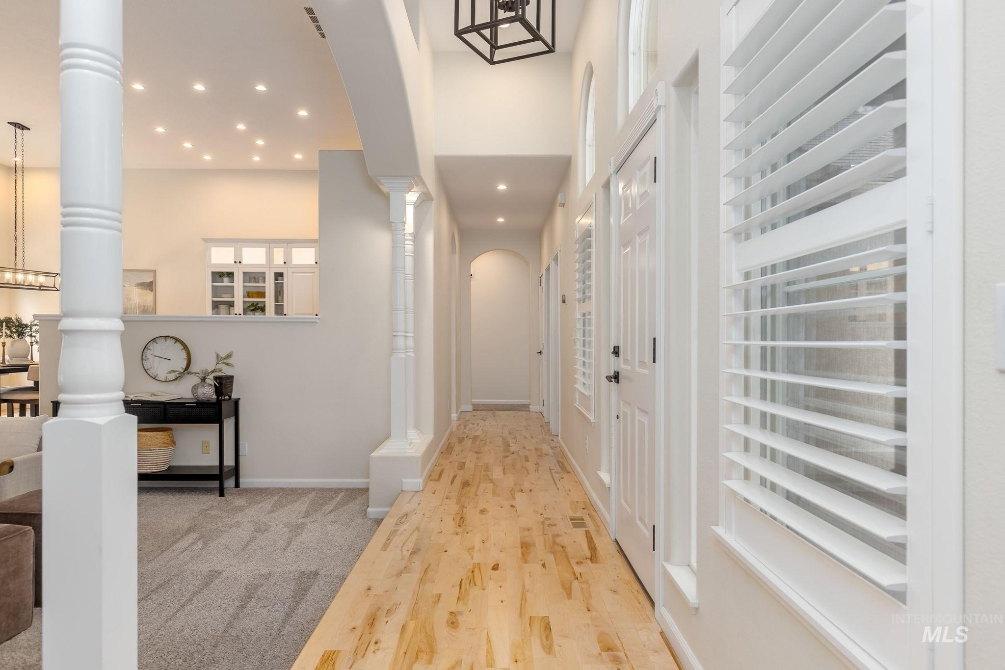 Hallway with light wood-type flooring, recessed lighting, ornate columns, and arched walkways