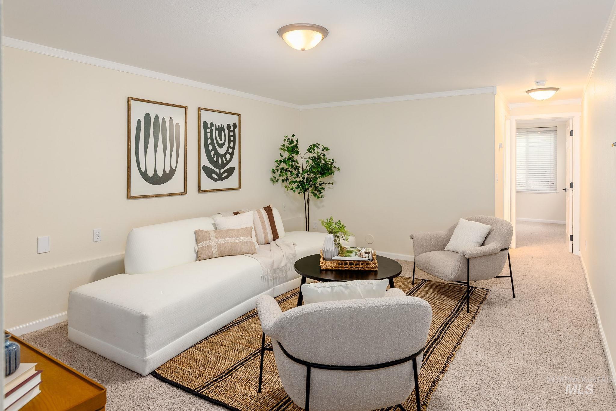 Carpeted living area with crown molding and baseboards