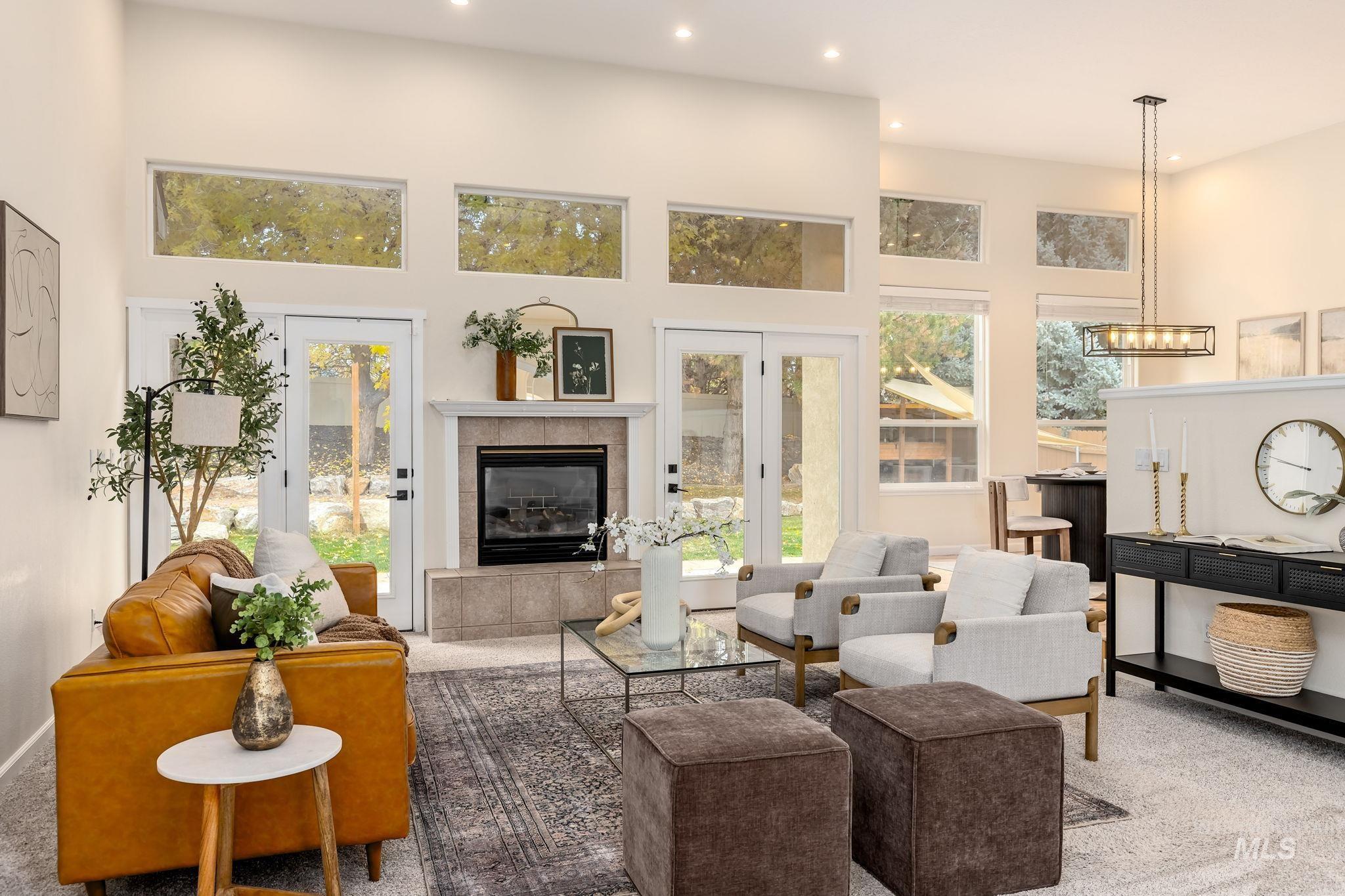 Living area featuring carpet flooring, a tile fireplace, plenty of natural light, recessed lighting, and a towering ceiling