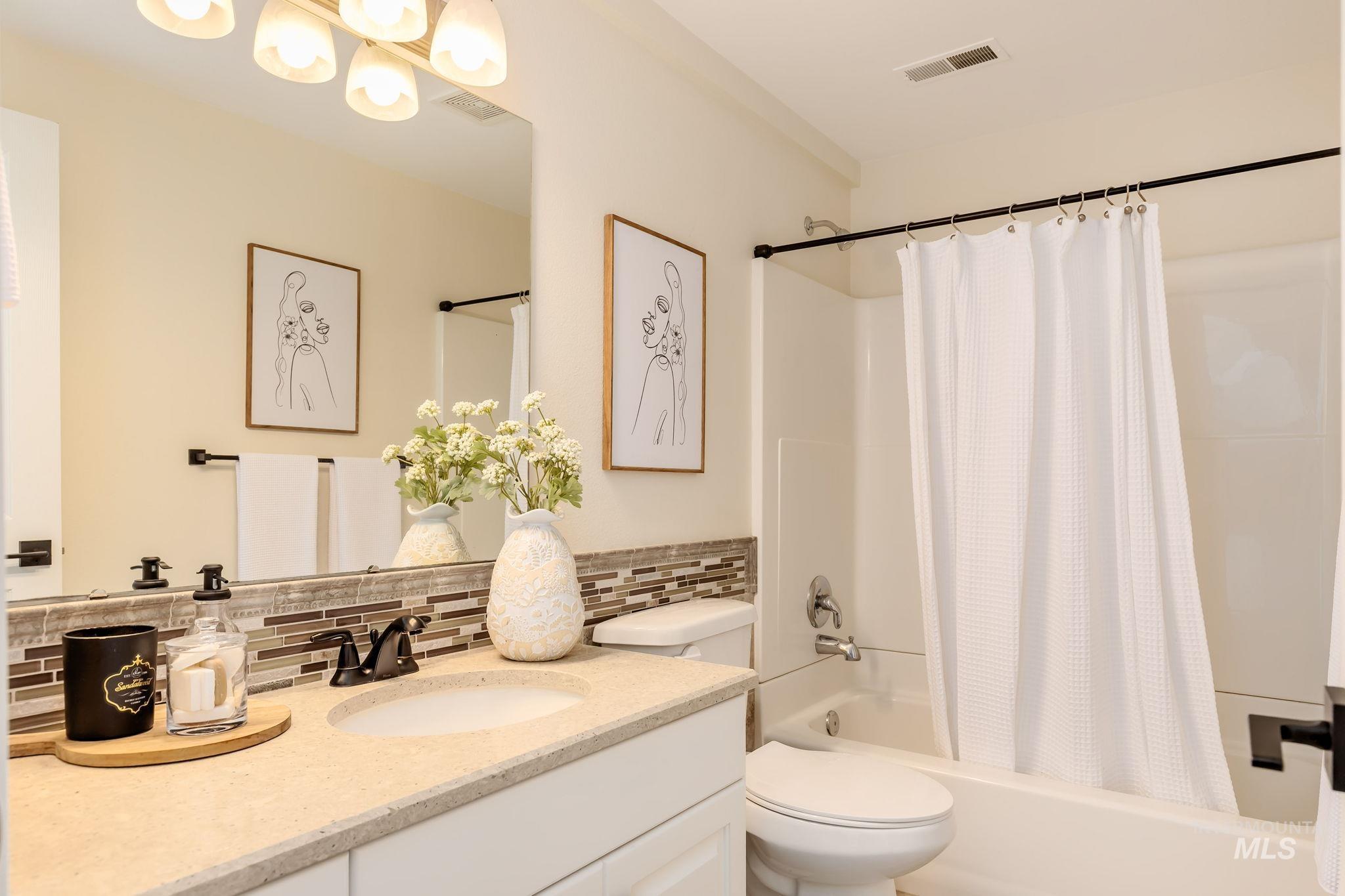 Full bath featuring shower / bath combo with shower curtain, decorative backsplash, and vanity