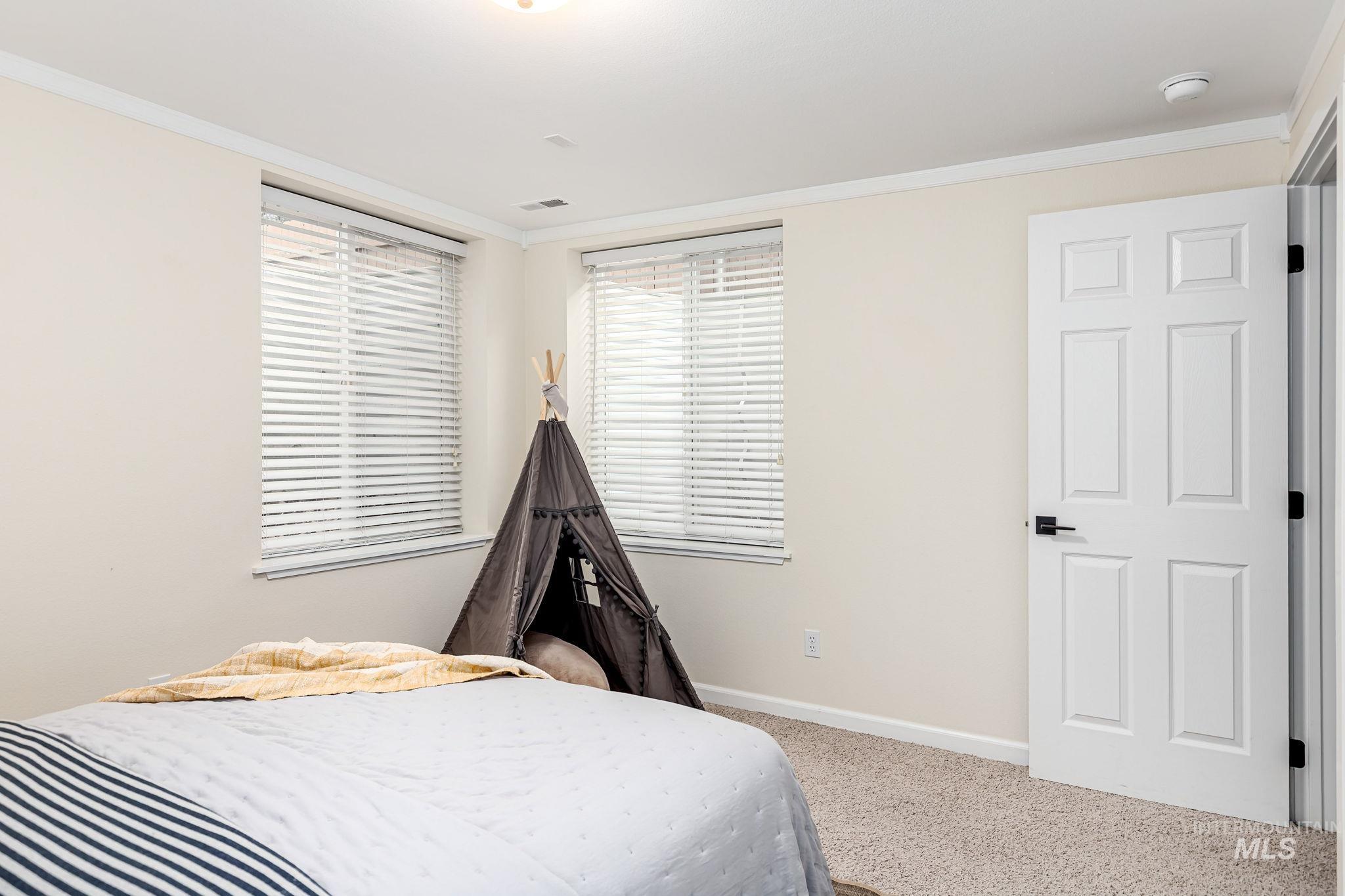 Carpeted bedroom with crown molding and baseboards