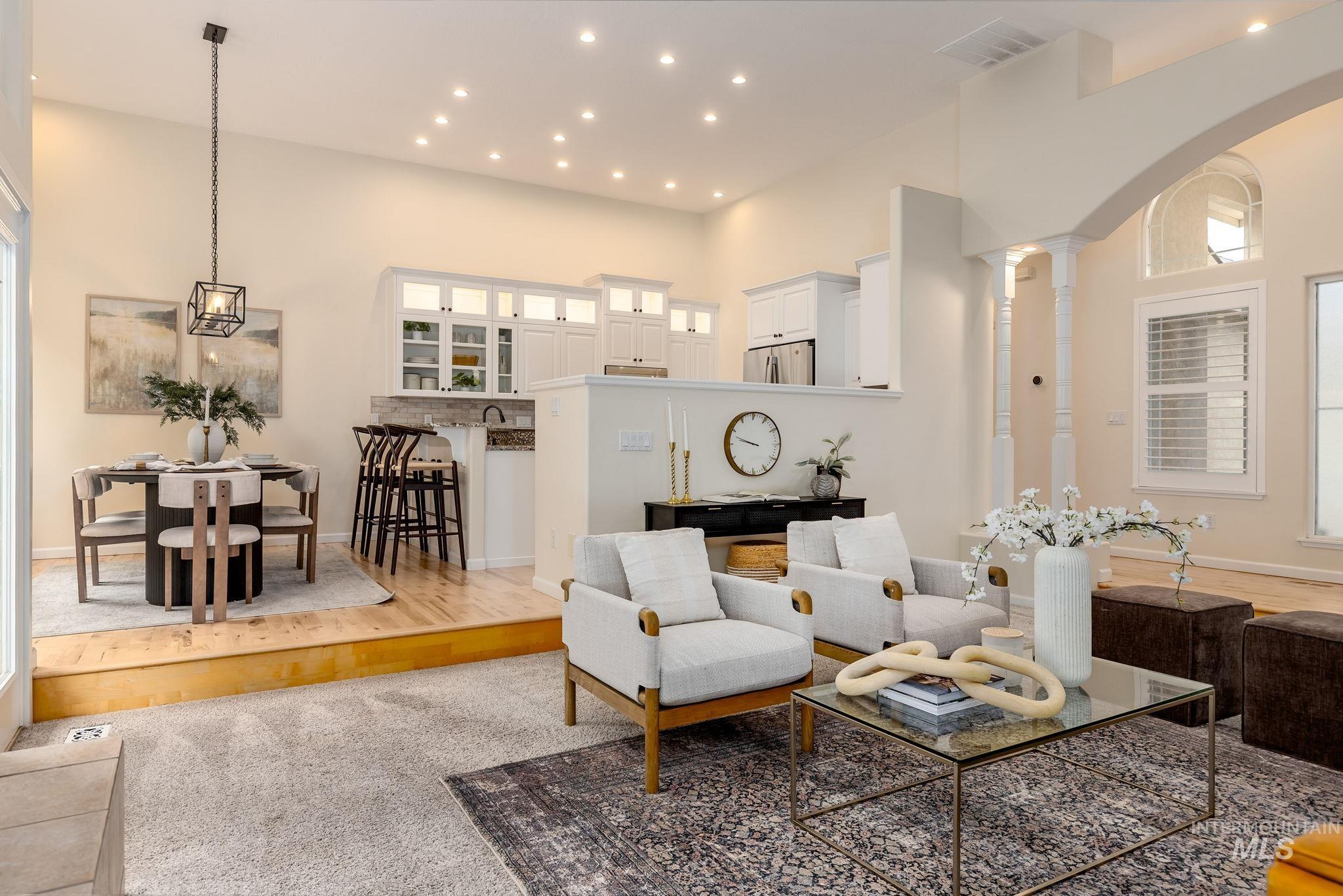 Living area featuring wood finished floors, a towering ceiling, and recessed lighting