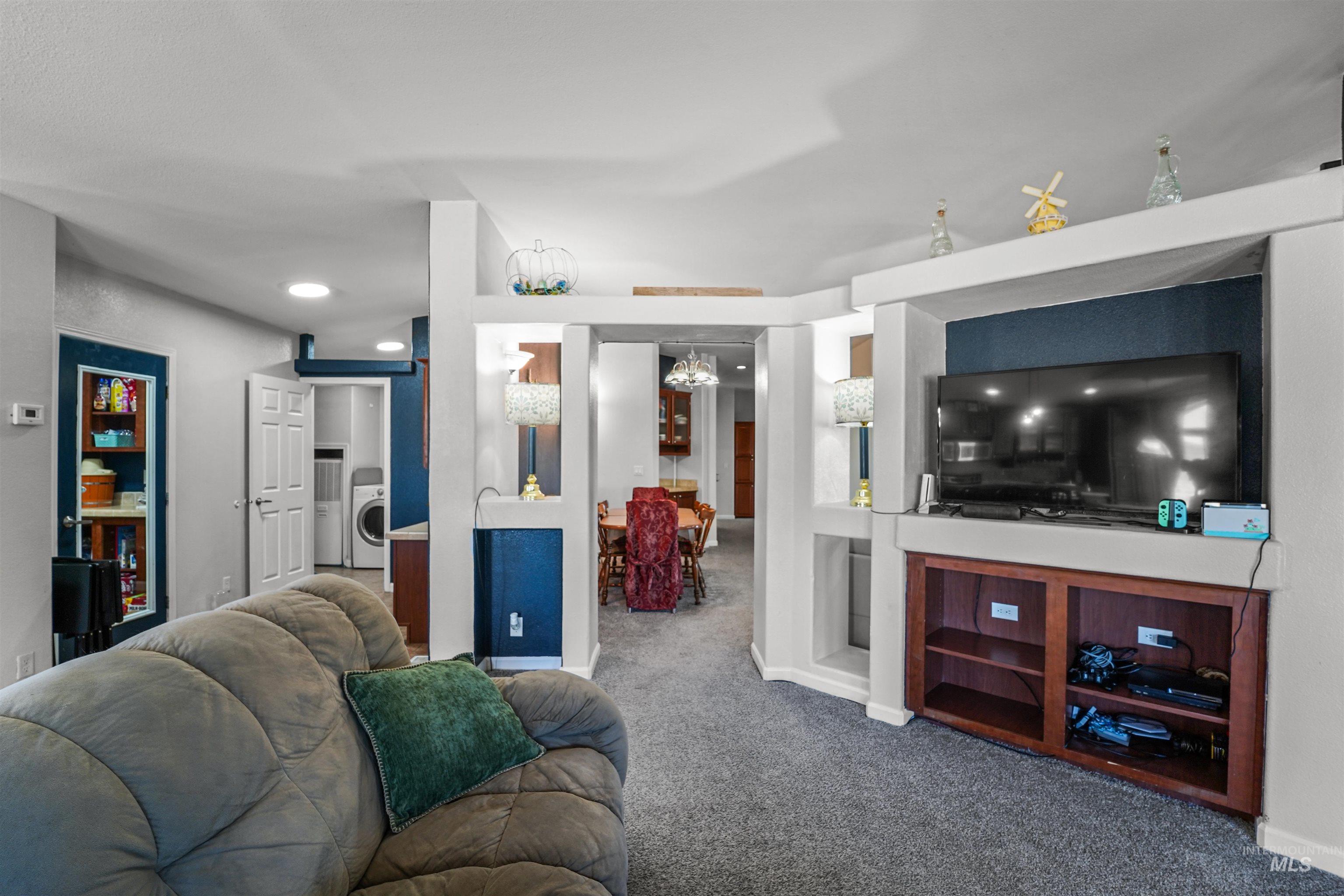 Living area with carpet floors, washer / dryer, and a chandelier