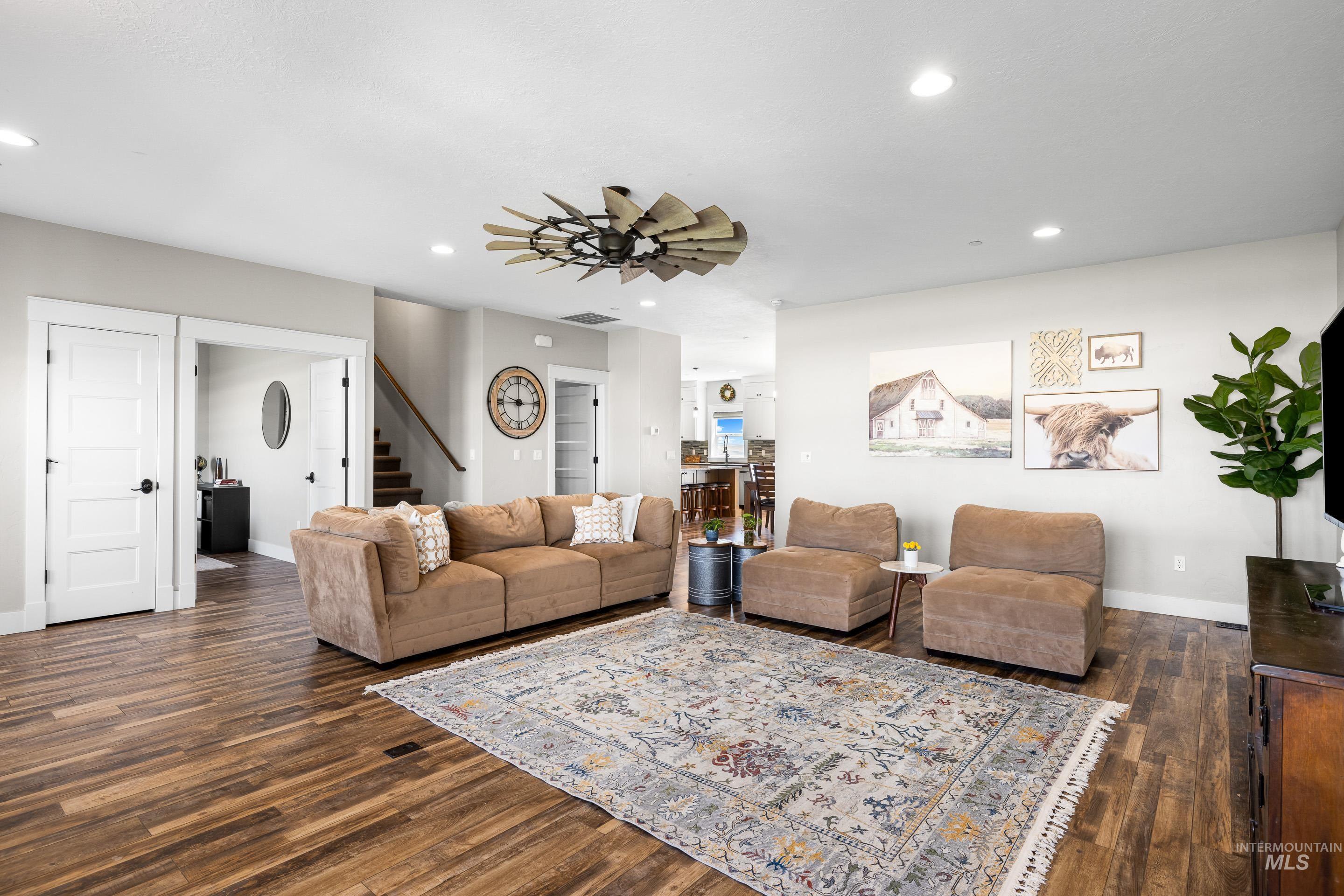 Living area featuring recessed lighting, dark wood-type flooring, stairway, and ceiling fan