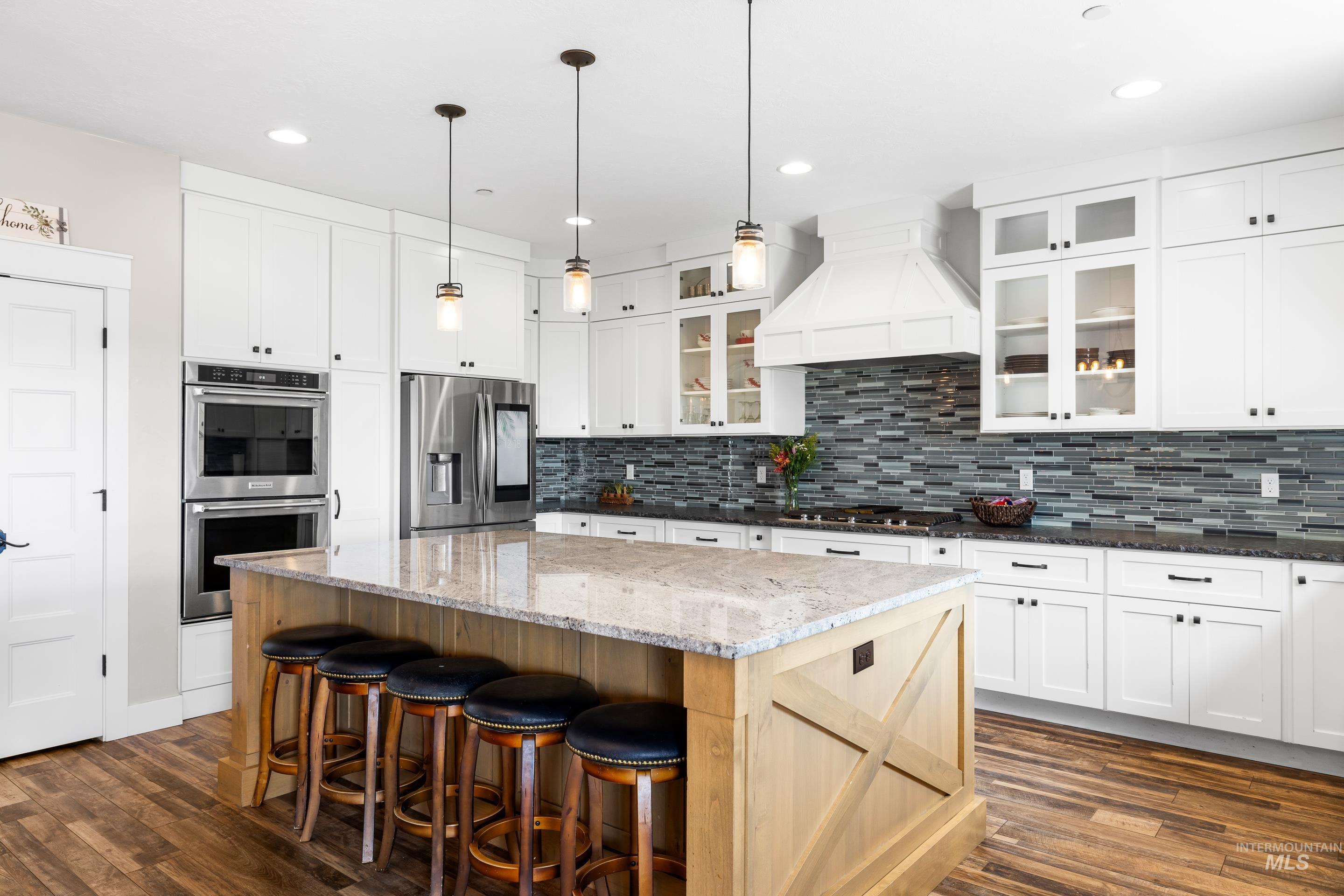 Kitchen with dark wood-style flooring, stainless steel appliances, dark stone counters, light brown cabinetry, and recessed lighting