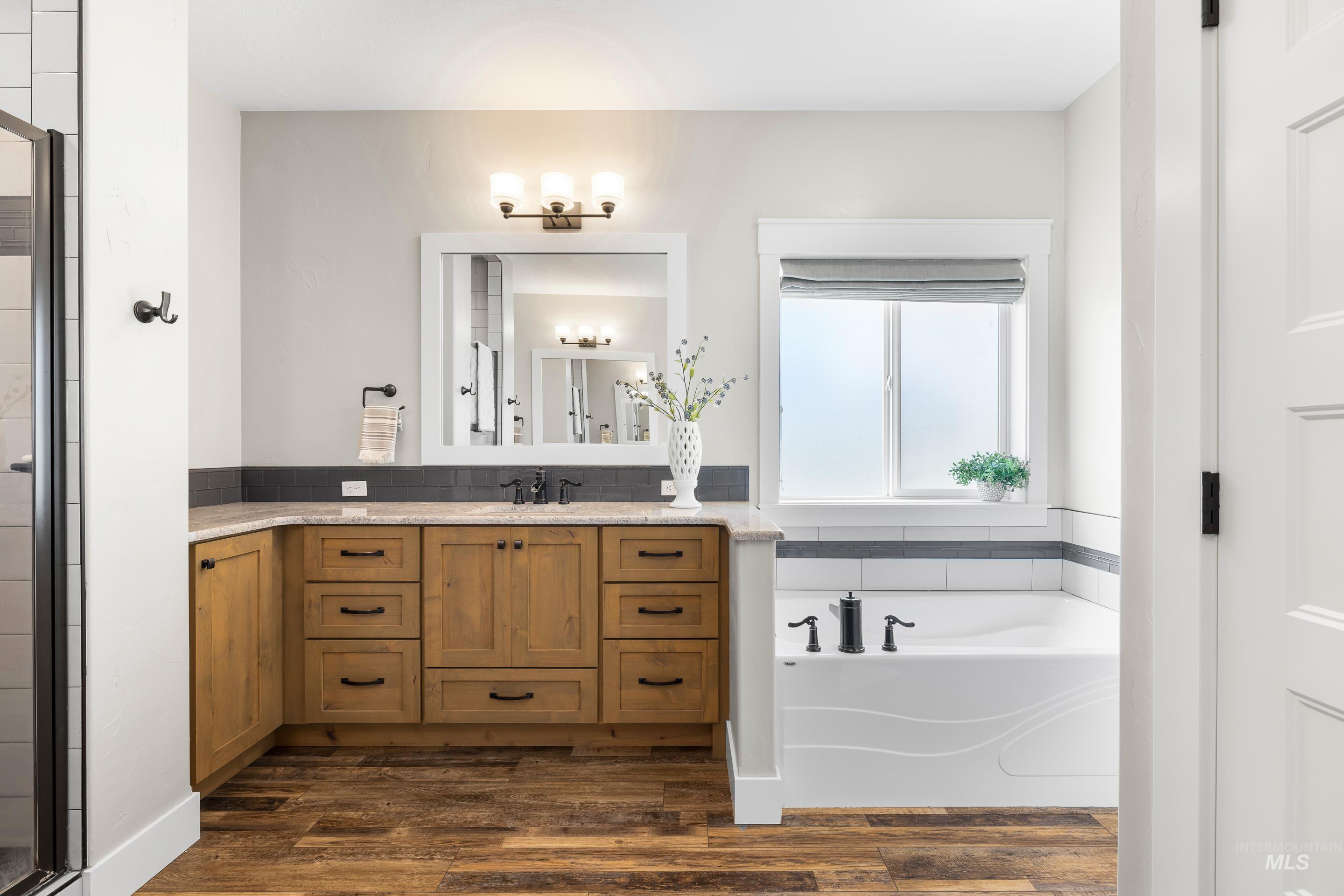 Bathroom with a garden tub, vanity, dark wood-type flooring, and a shower stall