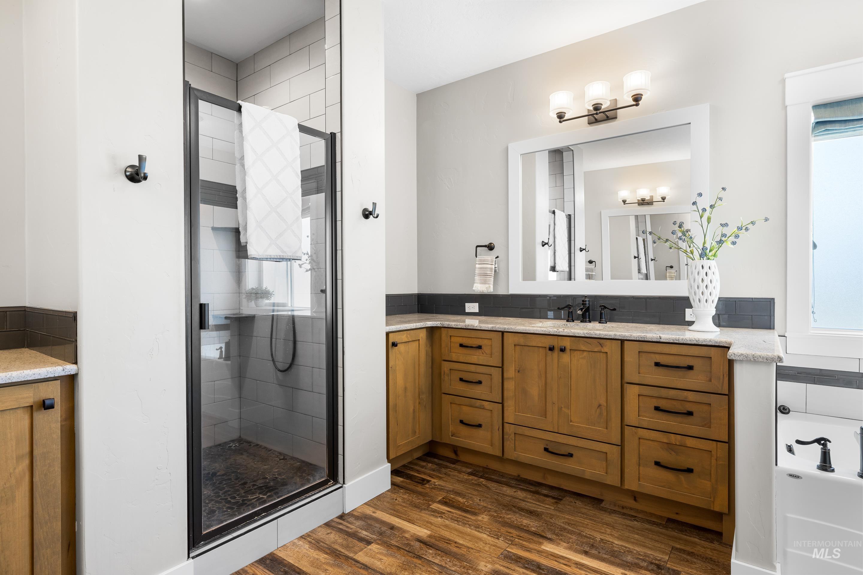 Full bathroom with a stall shower, dark wood-style flooring, vanity, and a bath