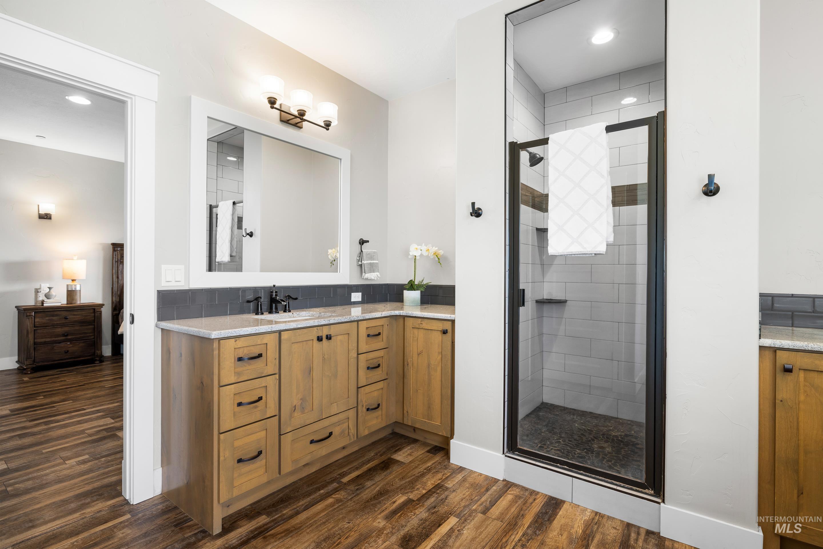 Full bathroom featuring a shower stall, vanity, dark wood-type flooring, recessed lighting, and tasteful backsplash