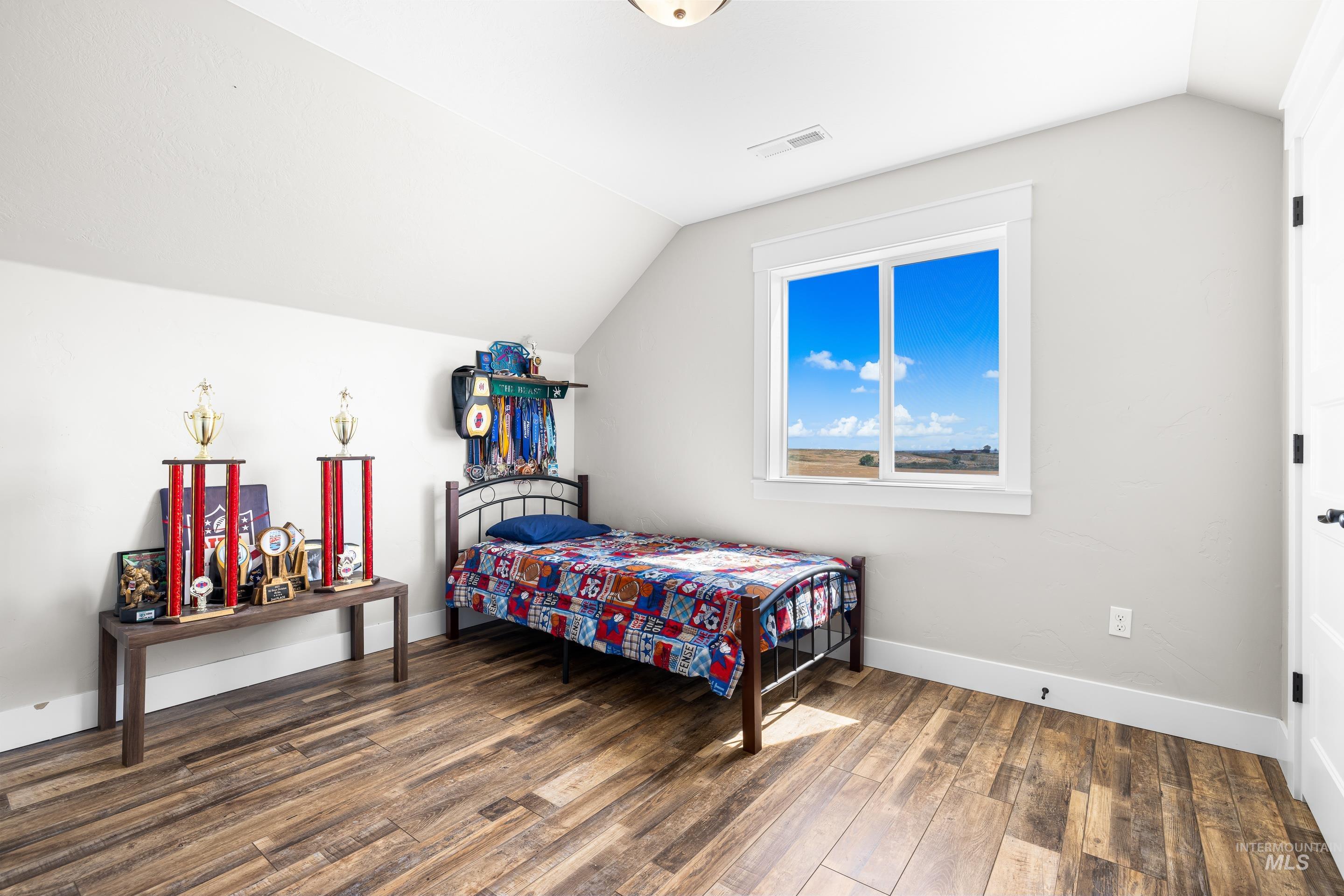 Bedroom with vaulted ceiling and dark wood-type flooring