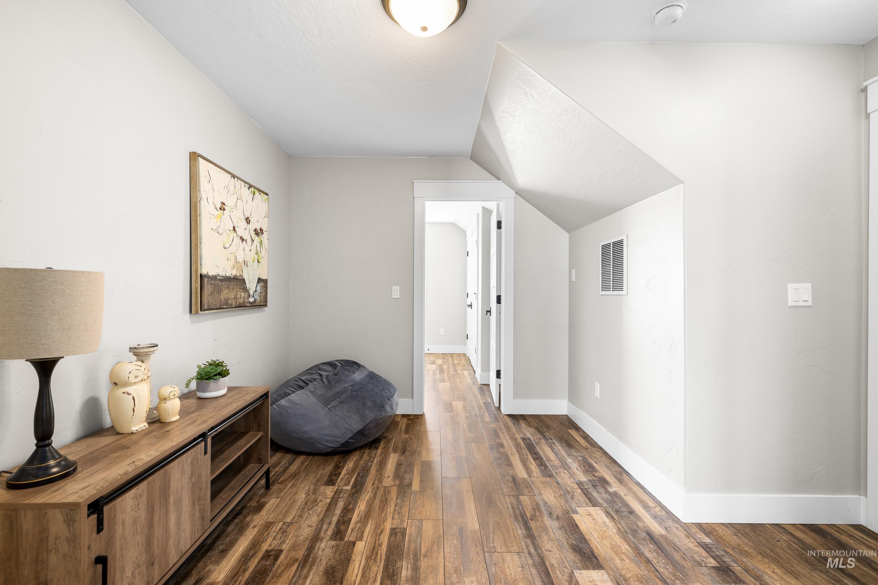 Corridor featuring dark wood-style flooring and vaulted ceiling