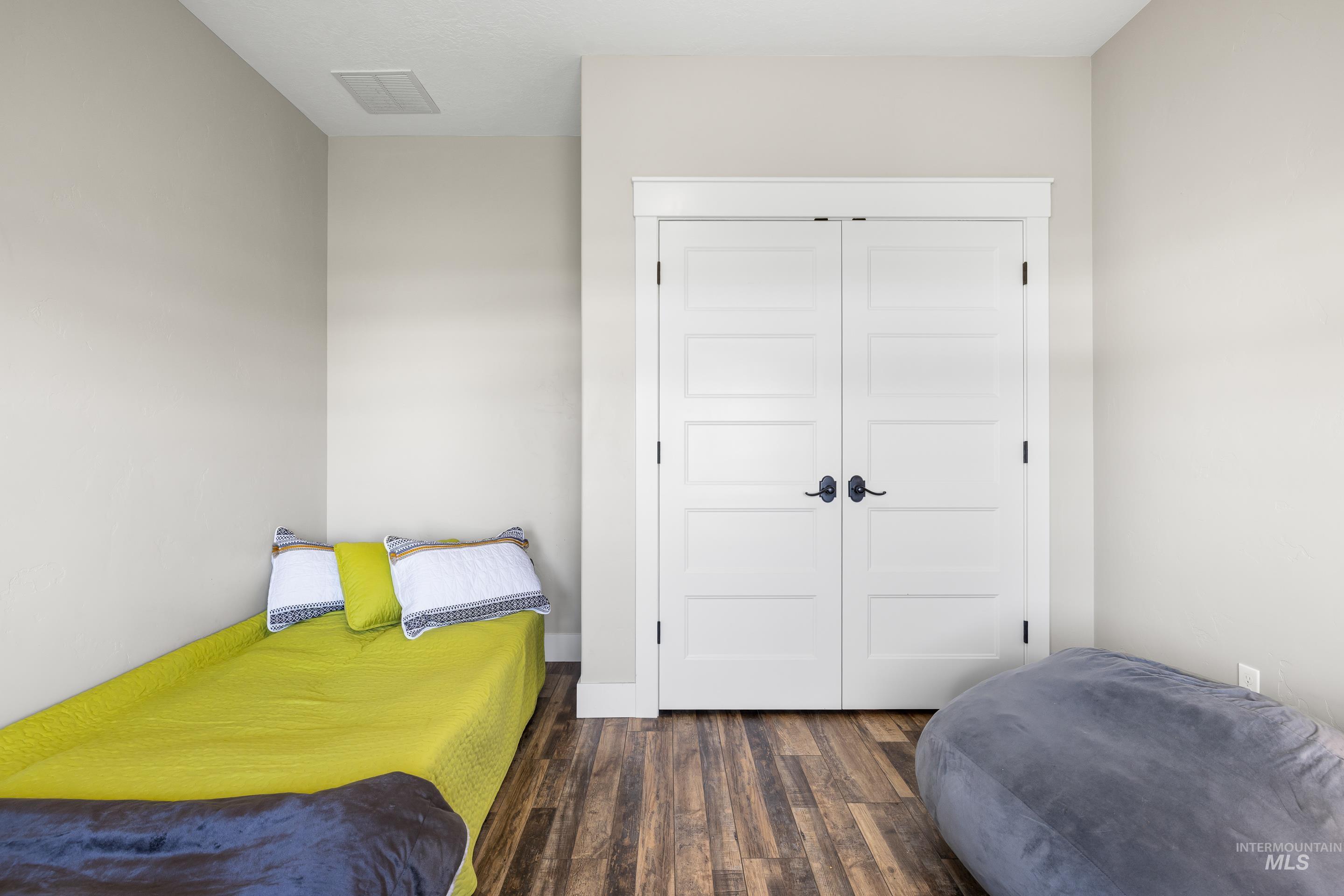 Bedroom with dark wood-type flooring and a closet