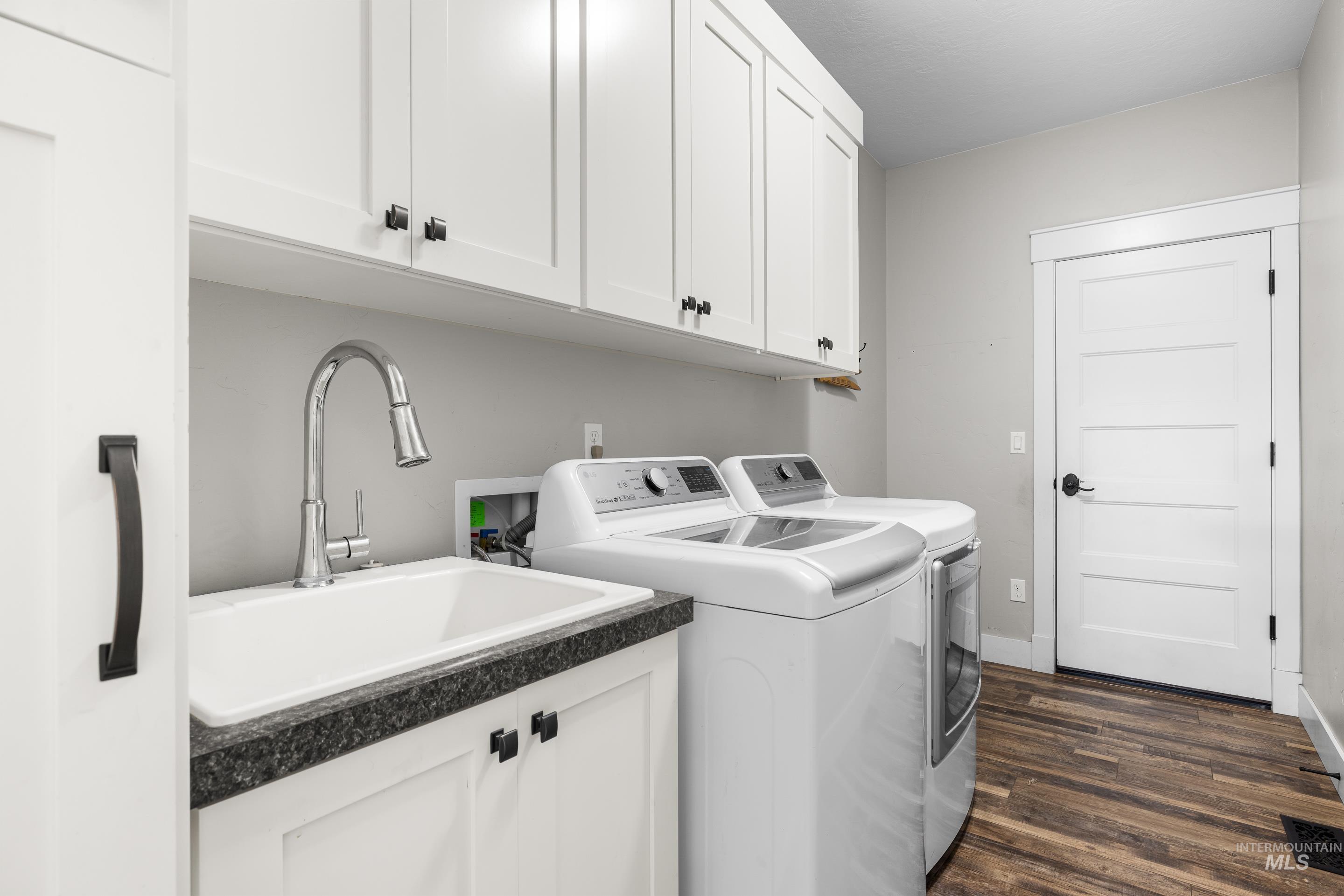 Laundry area with cabinet space, dark wood finished floors, and washer and dryer