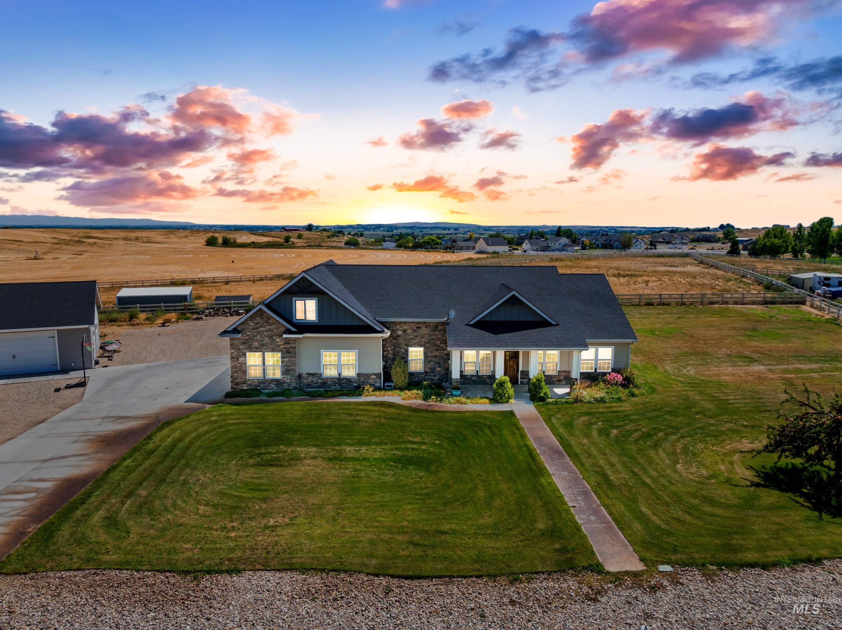 Craftsman inspired home with a porch, stone siding, a front yard, a view of rural / pastoral area, and driveway