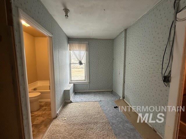 Bathroom featuring wallpapered walls and a bath
