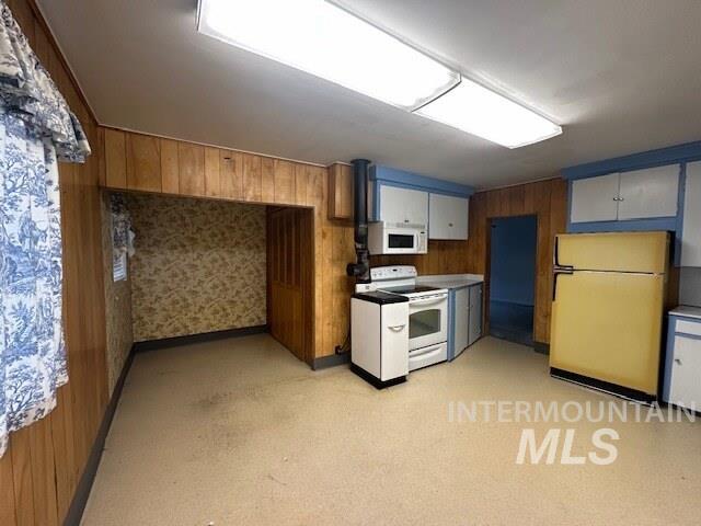 Kitchen featuring white appliances and wood walls