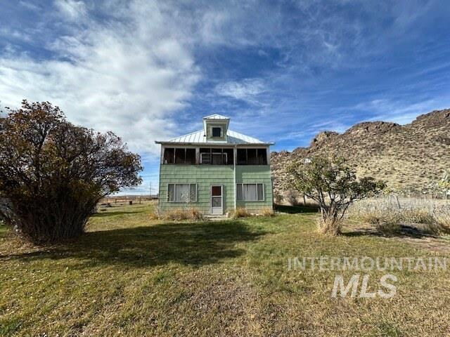 Rear view of property with a yard and a sunroom