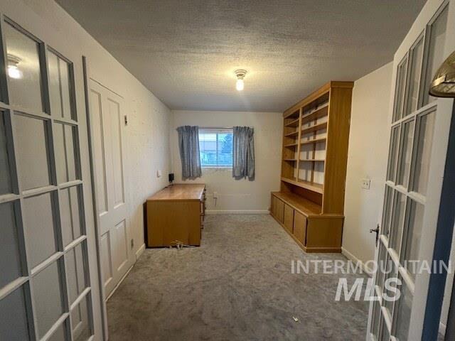 Unfurnished office with carpet floors, a textured ceiling, and french doors