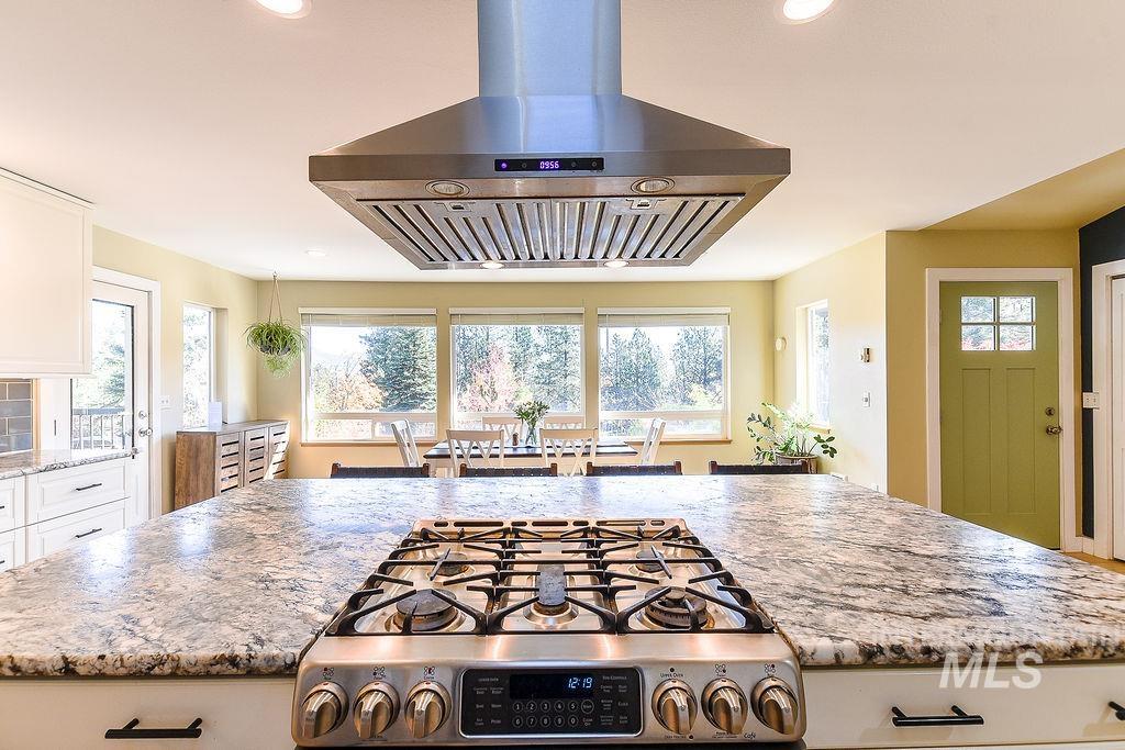 Kitchen featuring range hood, light stone countertops, white cabinets, and recessed lighting