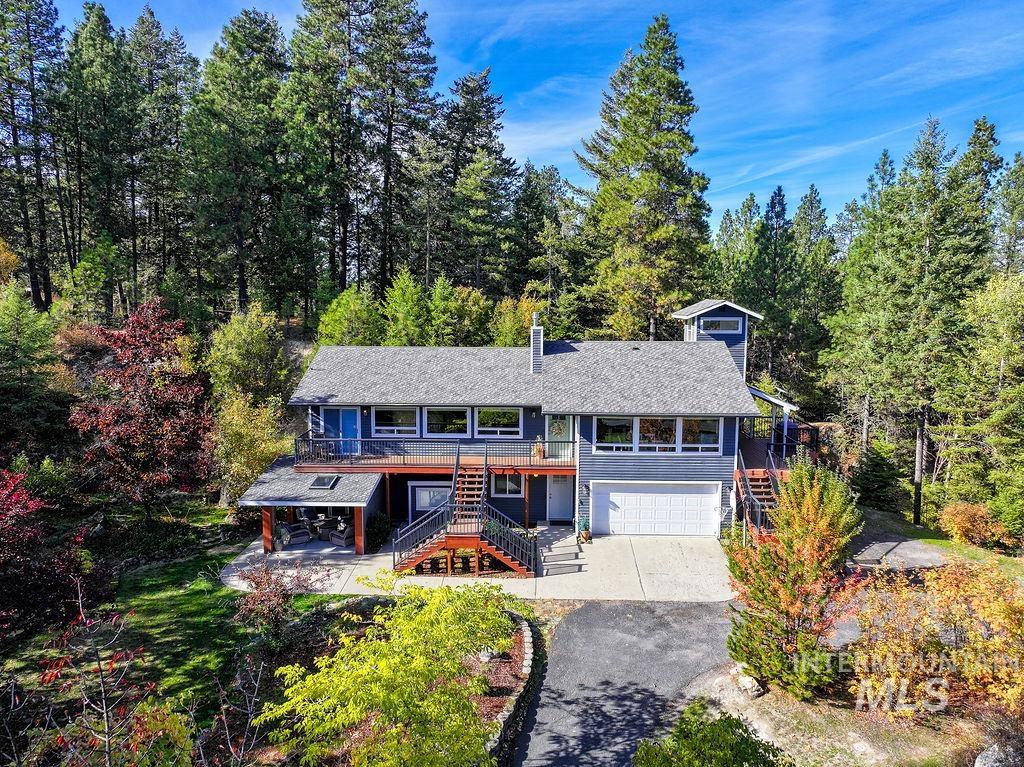 View of front of house featuring stairway, asphalt driveway, a garage, and a deck