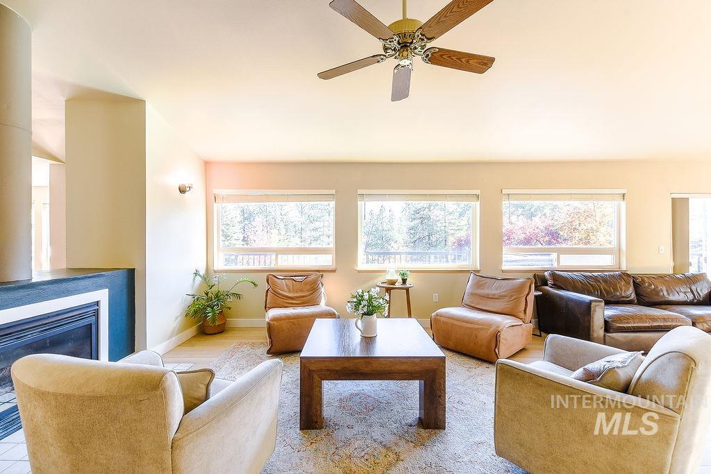 Living room featuring healthy amount of natural light, a glass covered fireplace, and a ceiling fan