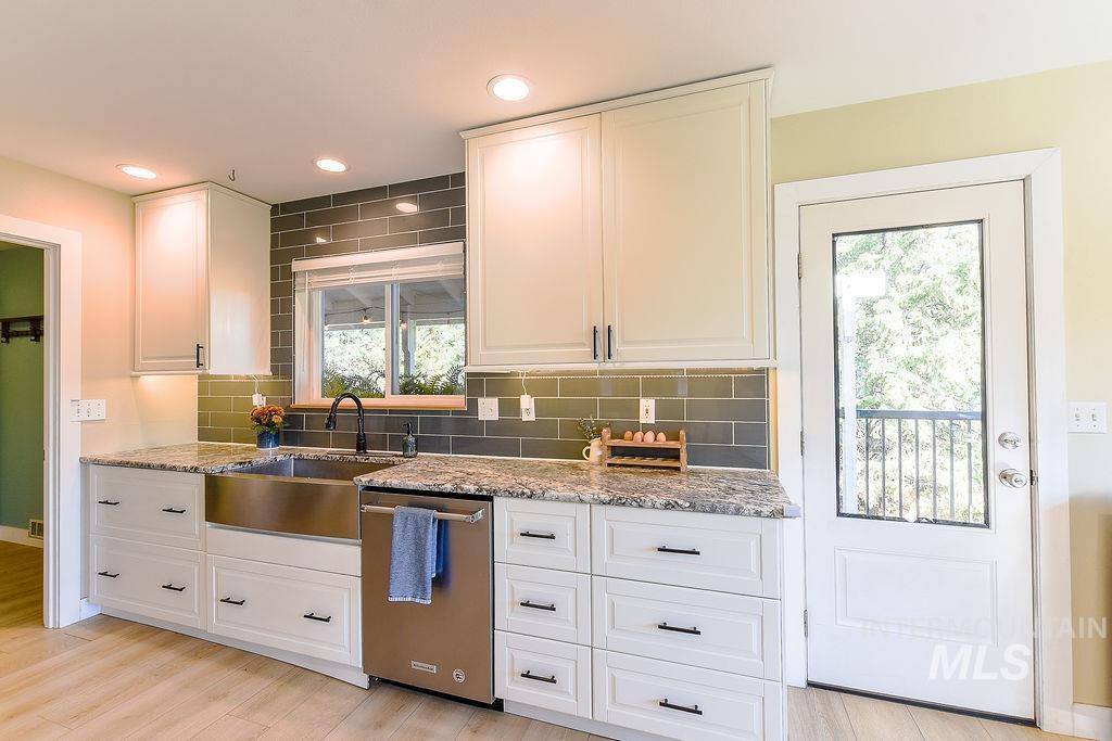 Kitchen featuring decorative backsplash, light stone countertops, dishwasher, recessed lighting, and light wood-style floors