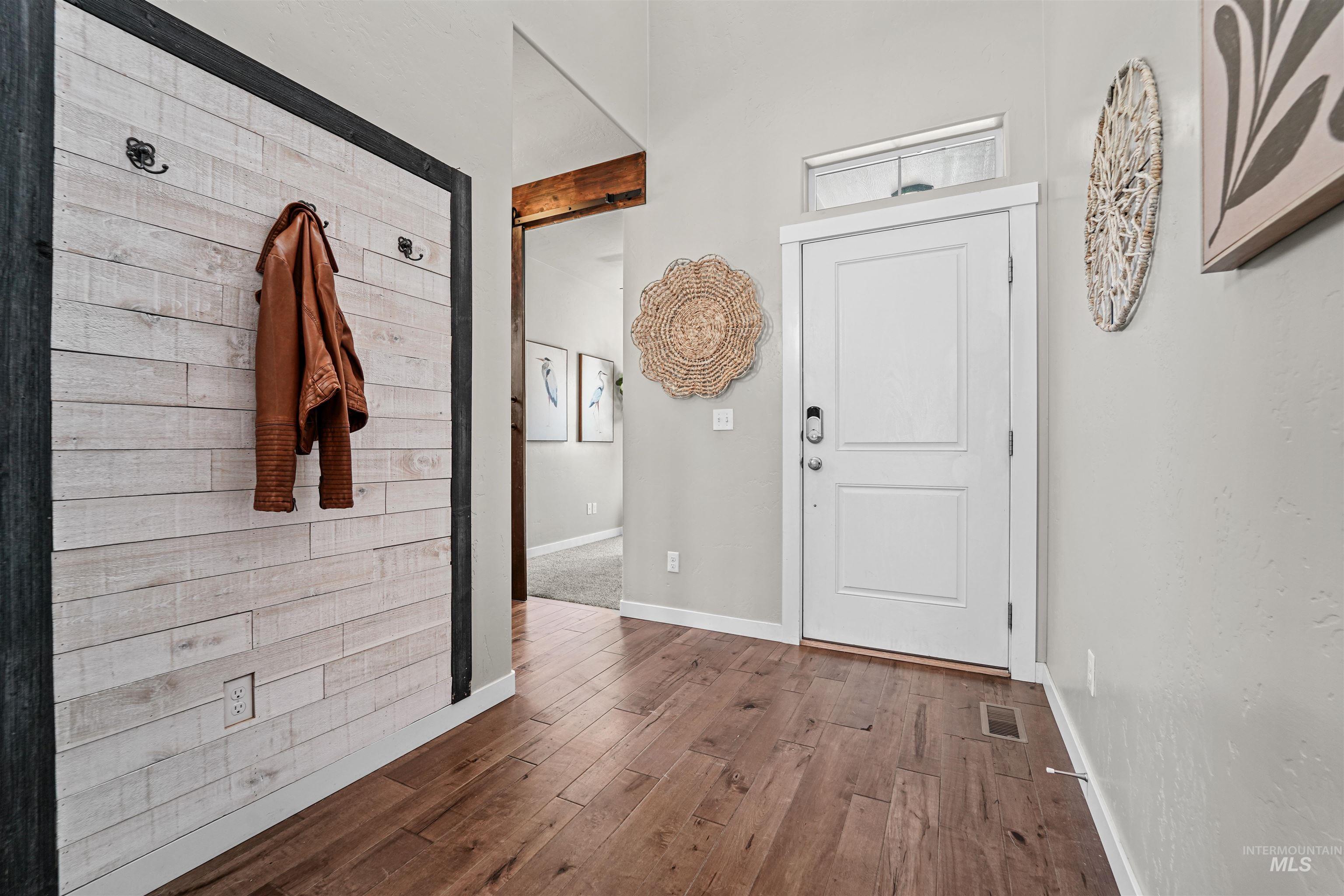 Foyer entrance featuring dark wood-style floors and wooden walls