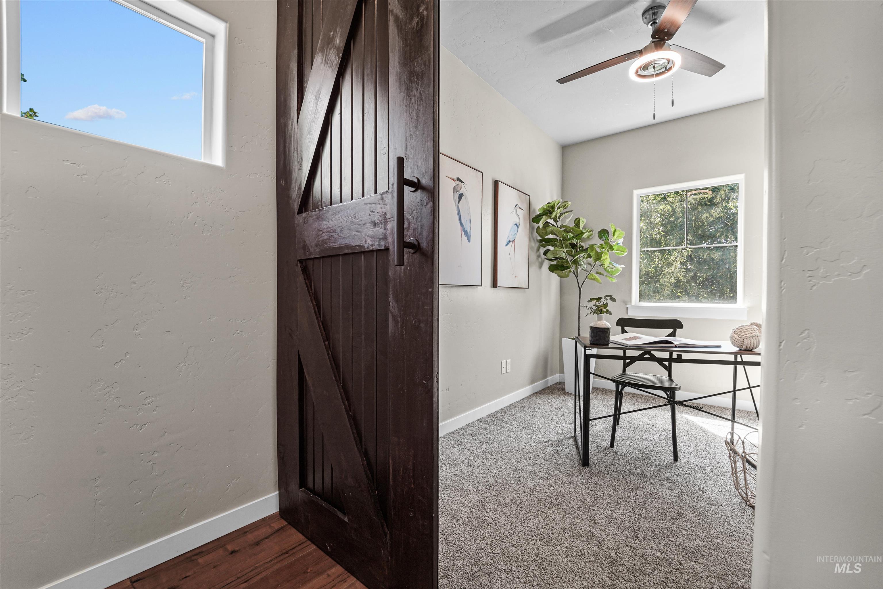 Home office featuring a textured wall, ceiling fan, and wood finished floors