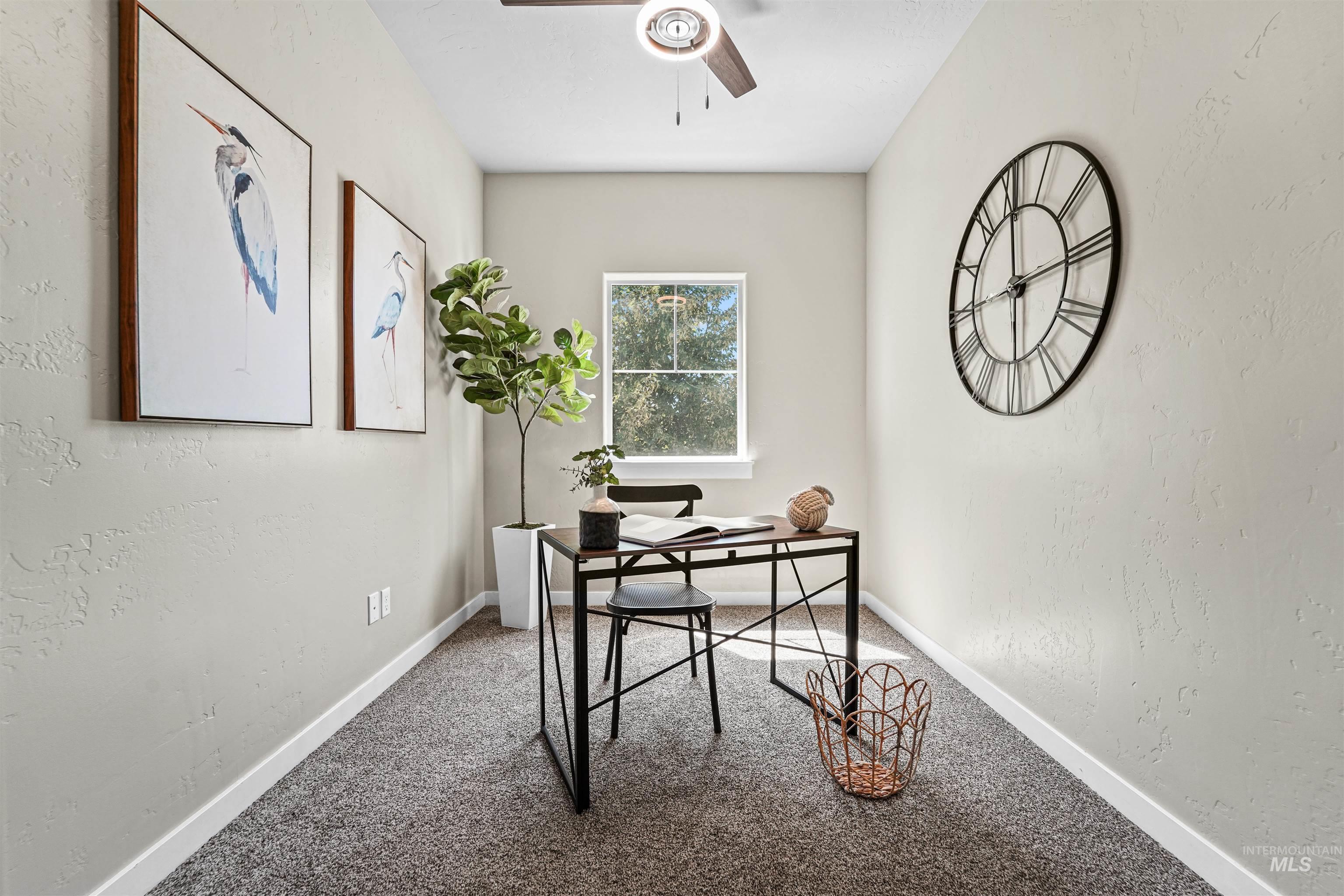 Office space with a textured wall, carpet, and a ceiling fan