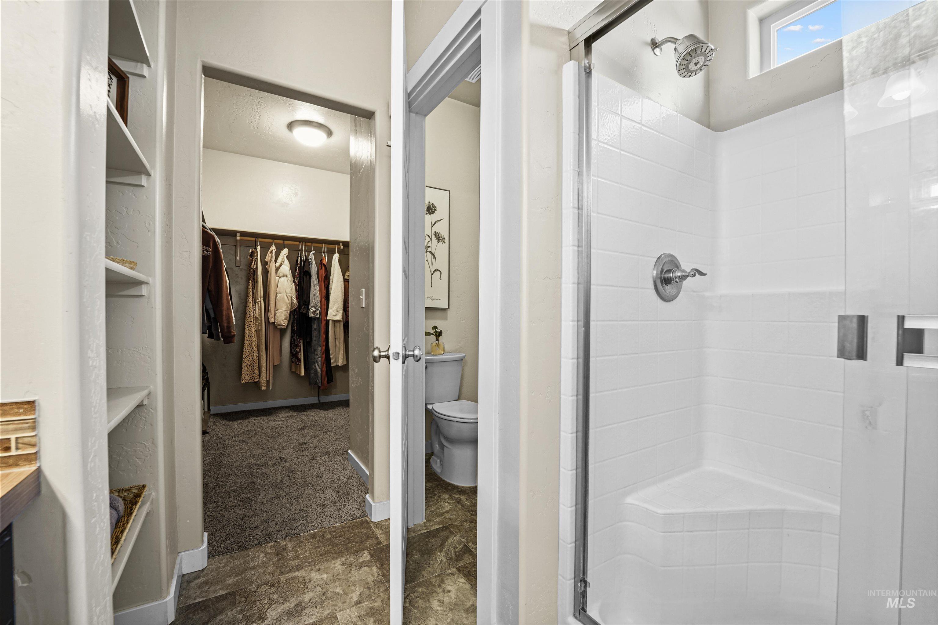 Full bath with a shower stall and a walk in closet