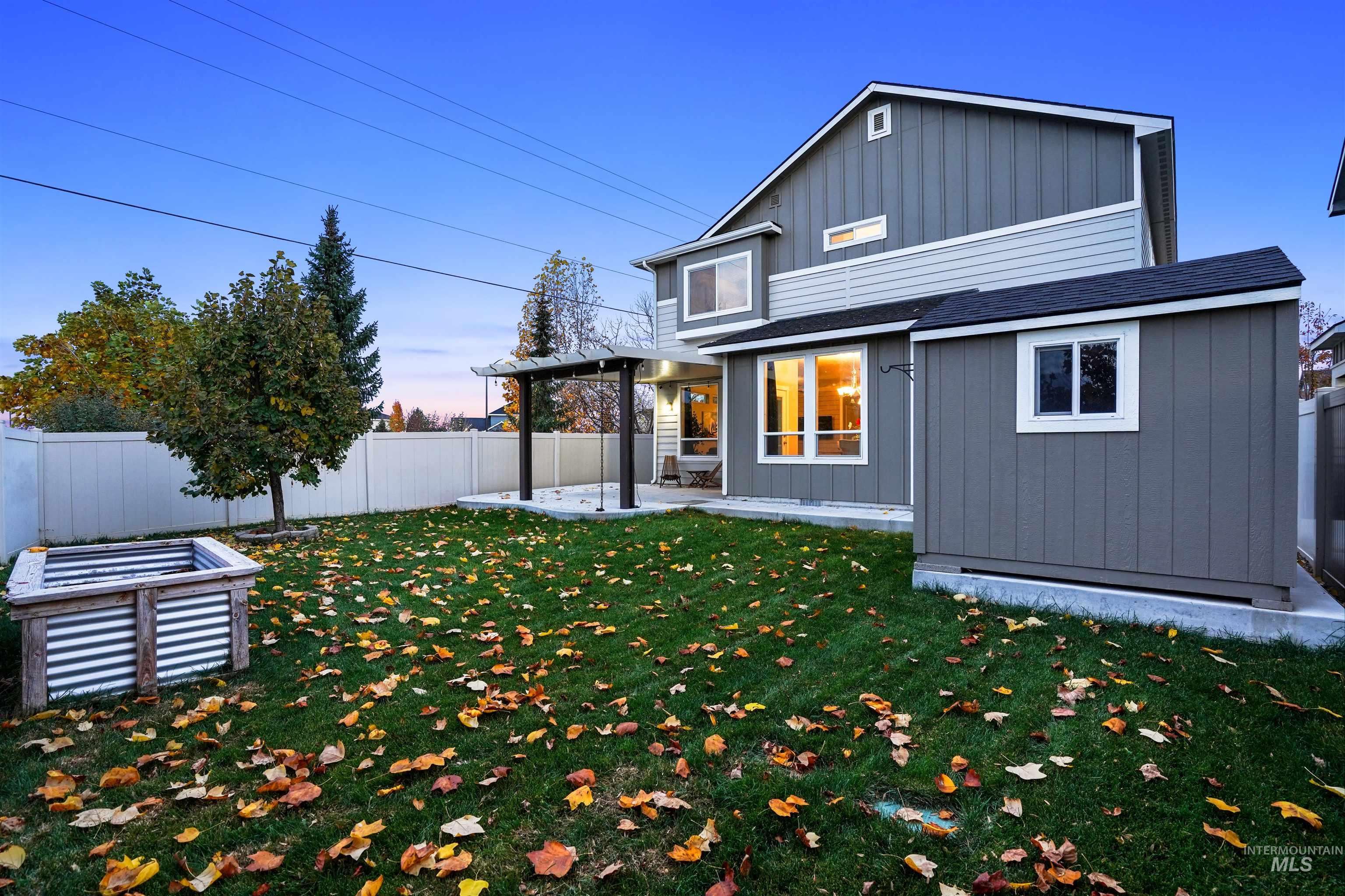 Back of property with board and batten siding, a patio, a fenced backyard, and roof with shingles