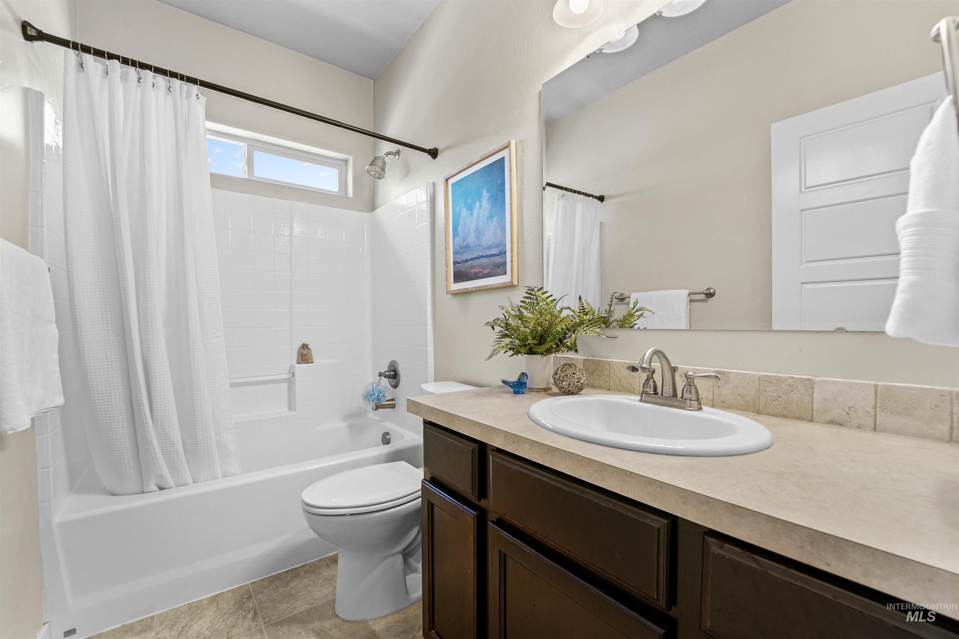 Bathroom with shower / bath combo with shower curtain, vanity, and light tile patterned floors