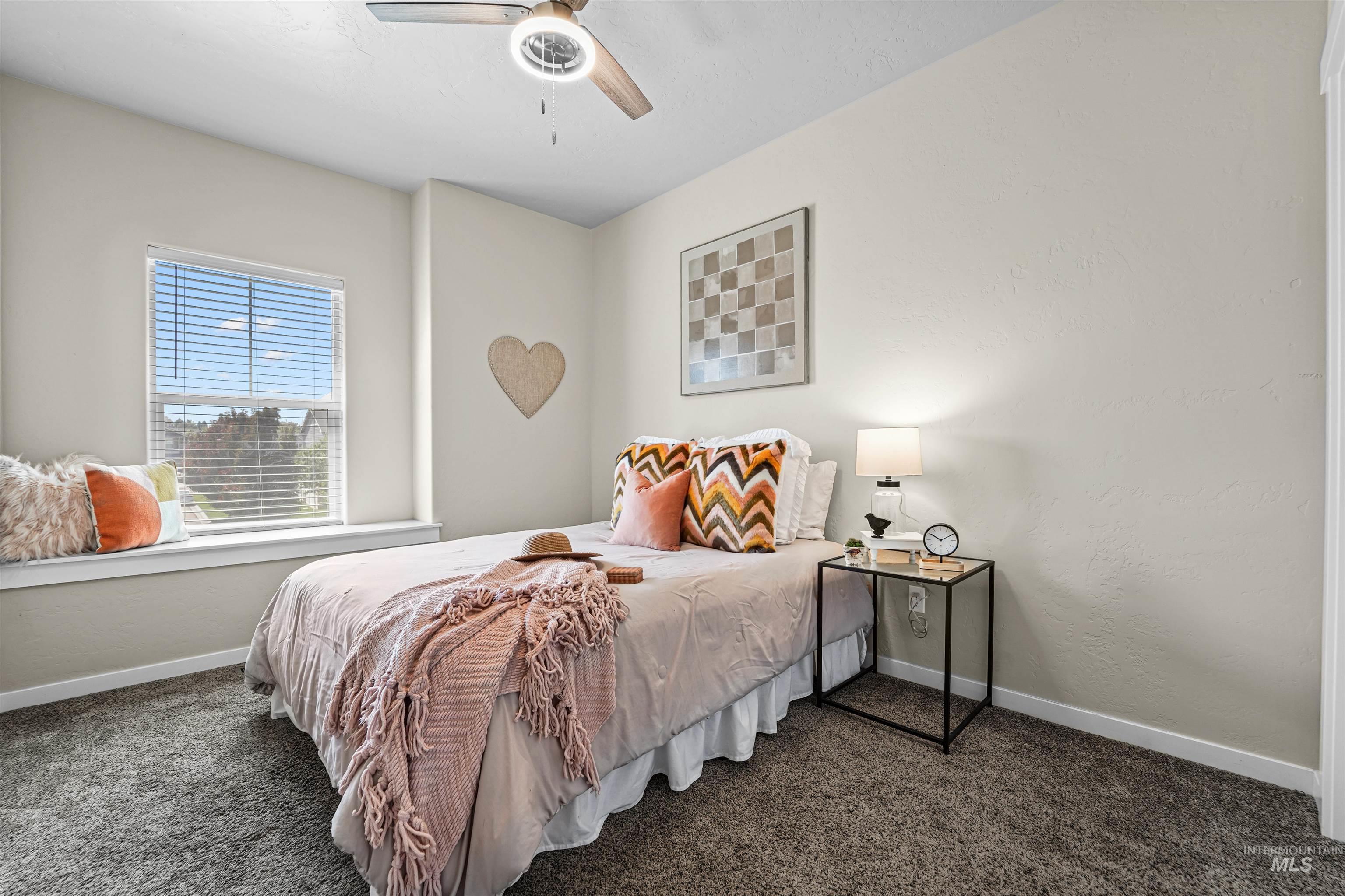Bedroom featuring dark carpet, ceiling fan, and a textured wall