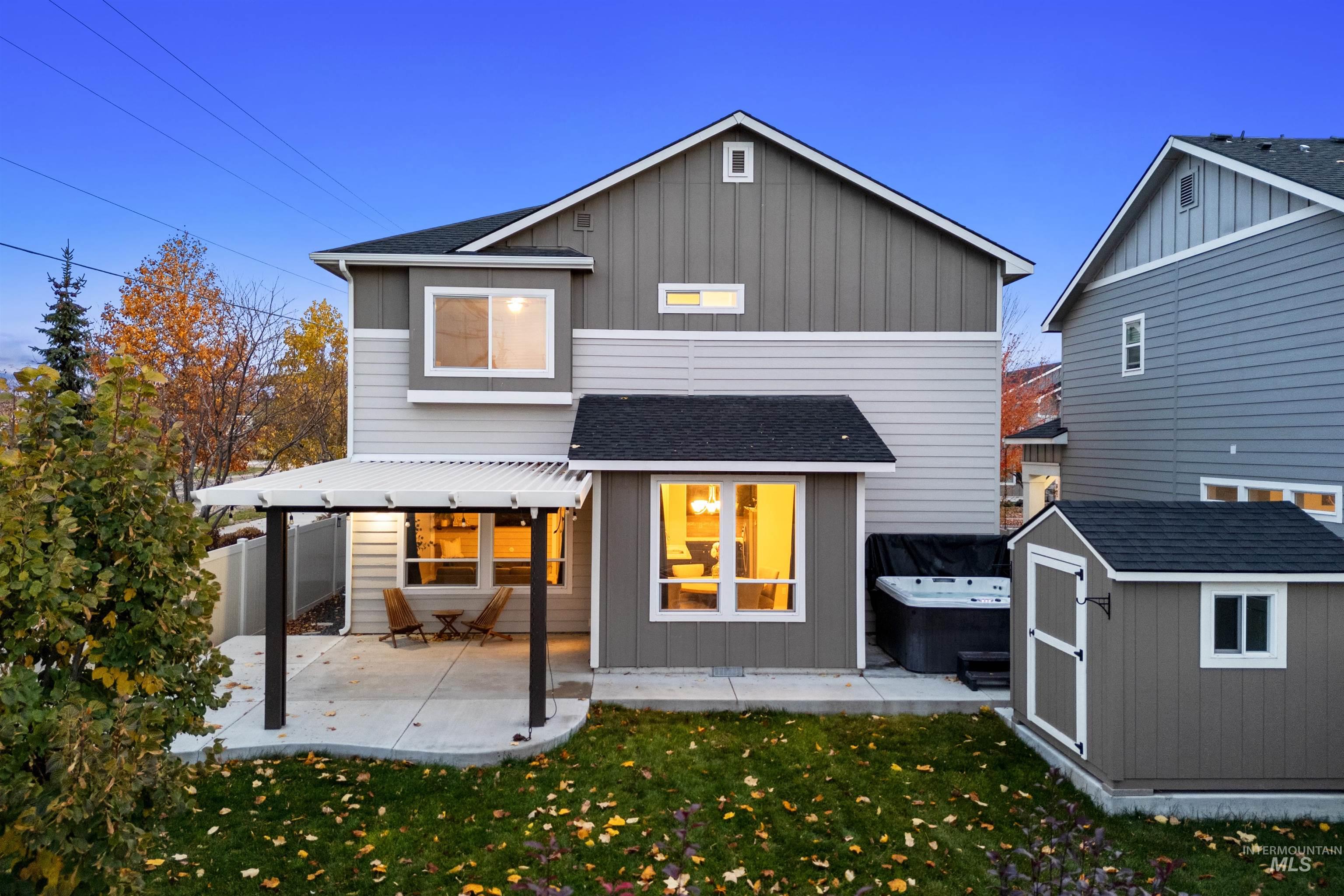 Rear view of property with a lawn, a patio, a storage unit, and board and batten siding