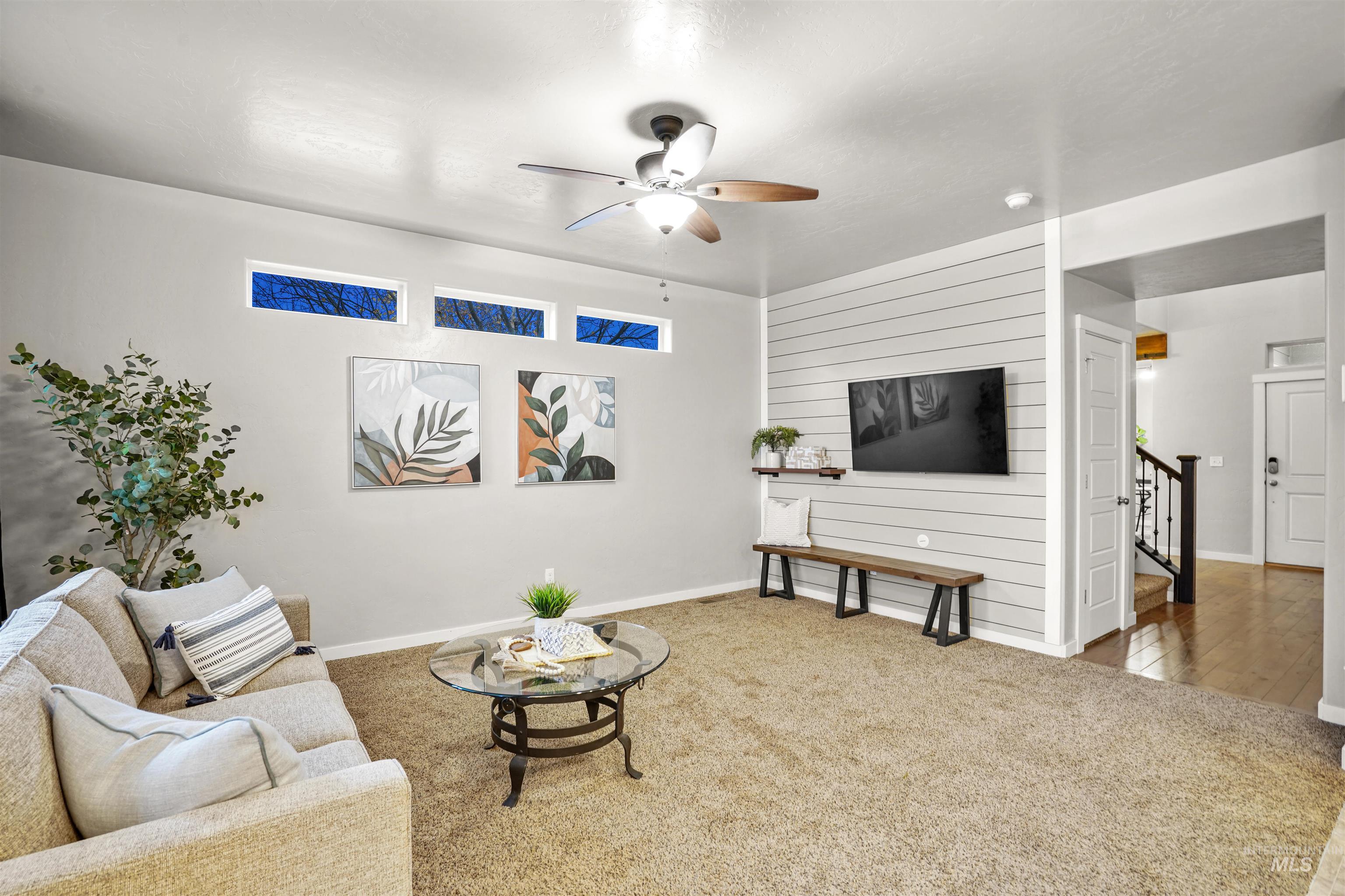 Living room featuring carpet flooring, a ceiling fan, and wood walls