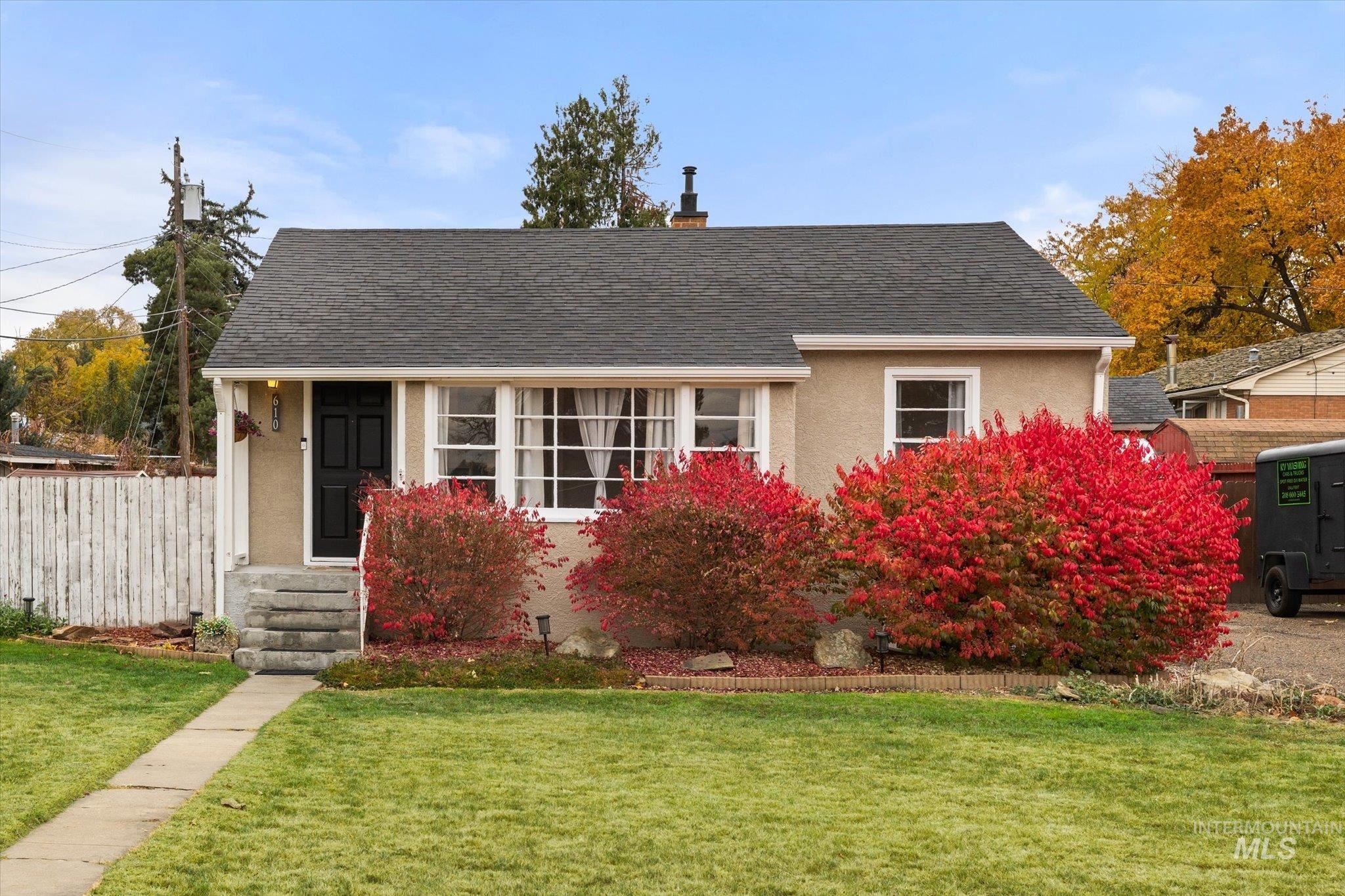 View of front facade with stucco siding, roof with shingles, and a chimney
