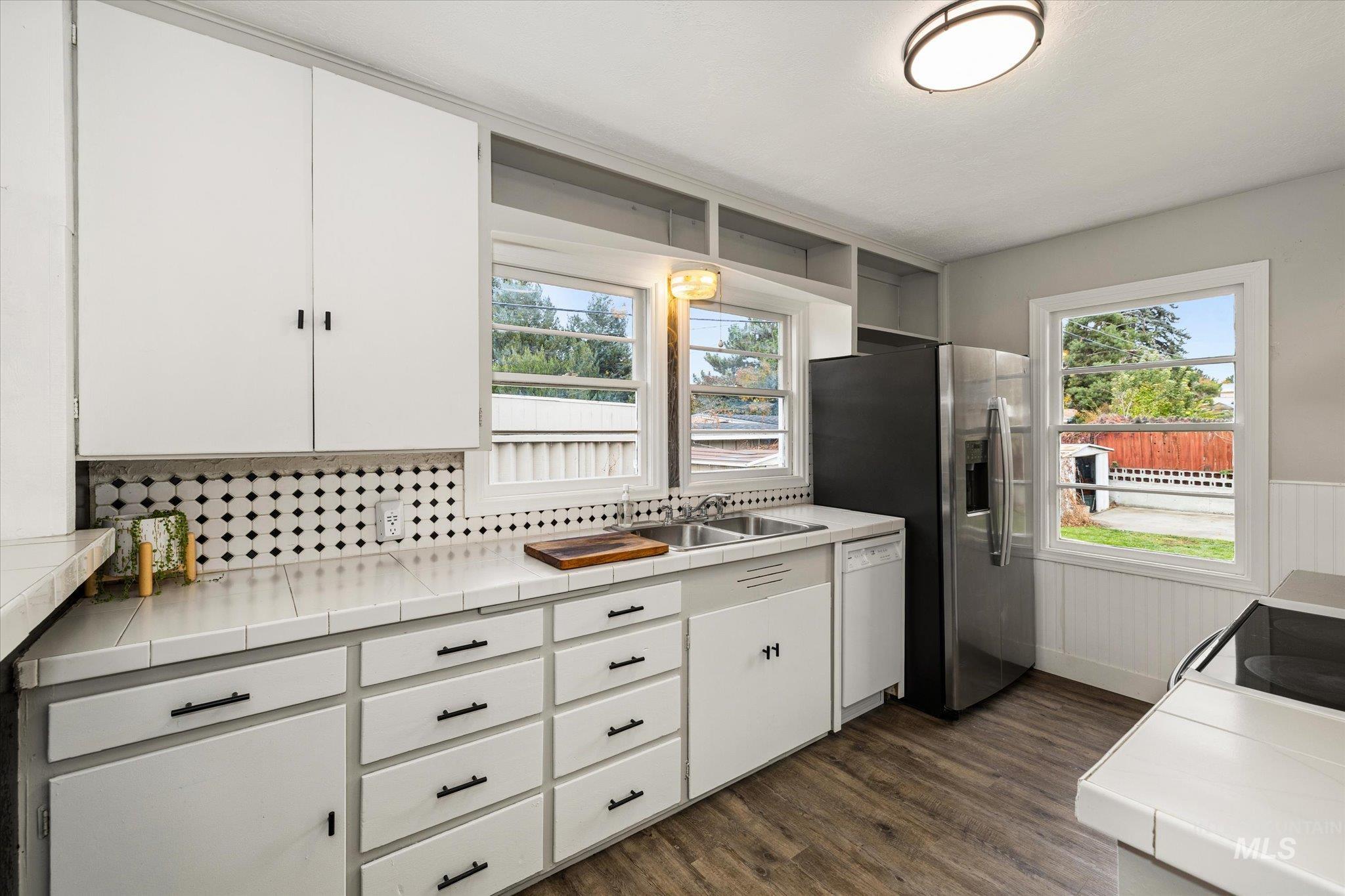 Kitchen featuring tile counters, white cabinets, dark wood-style floors, open shelves, and dishwasher