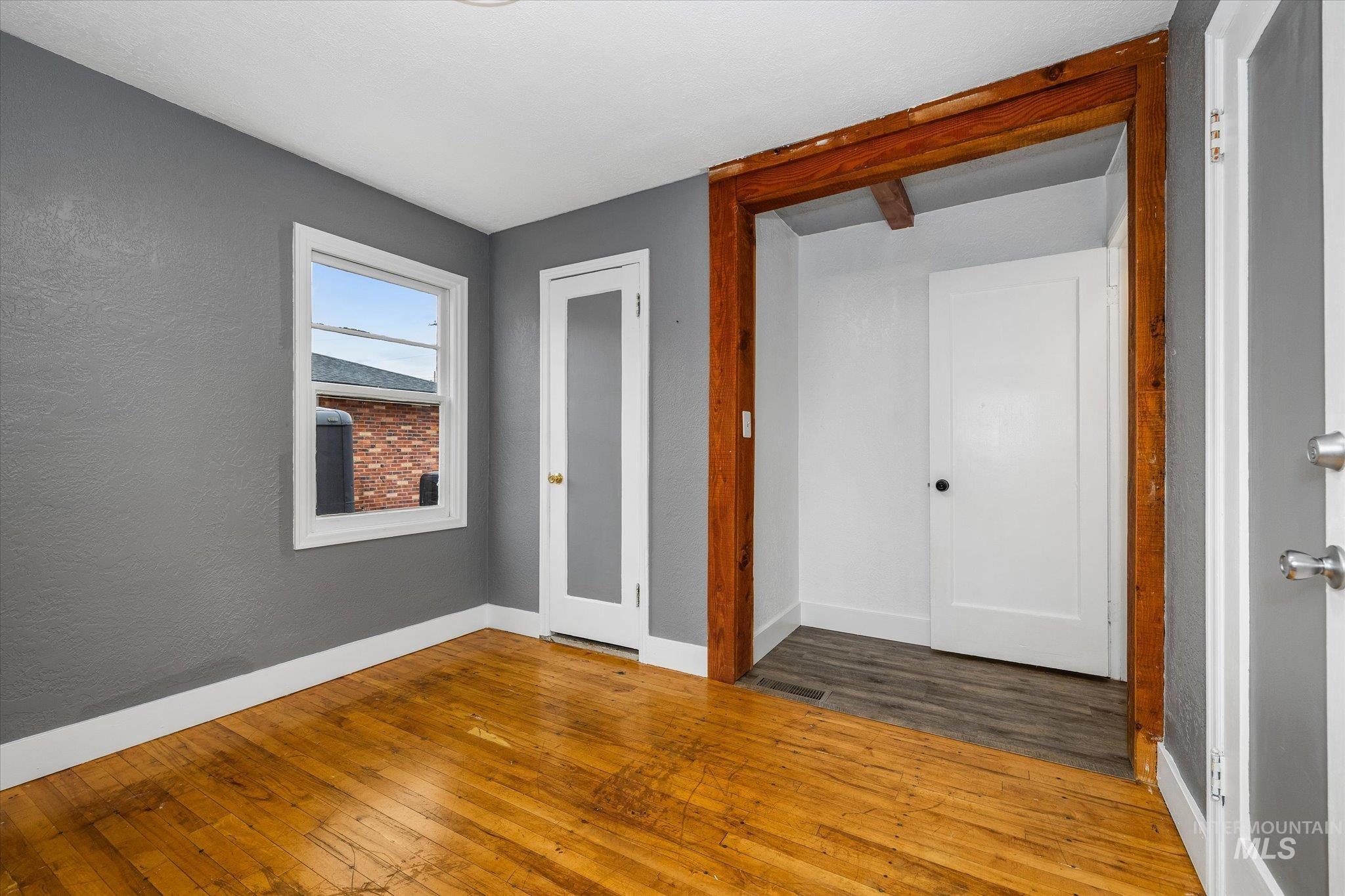 Unfurnished bedroom with hardwood / wood-style floors and a textured wall
