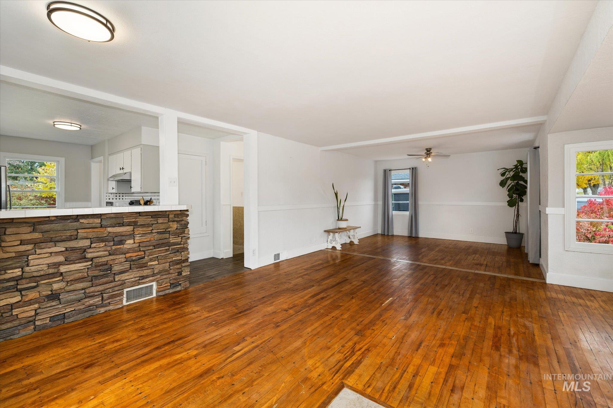 Unfurnished living room with plenty of natural light, dark wood finished floors, and ceiling fan