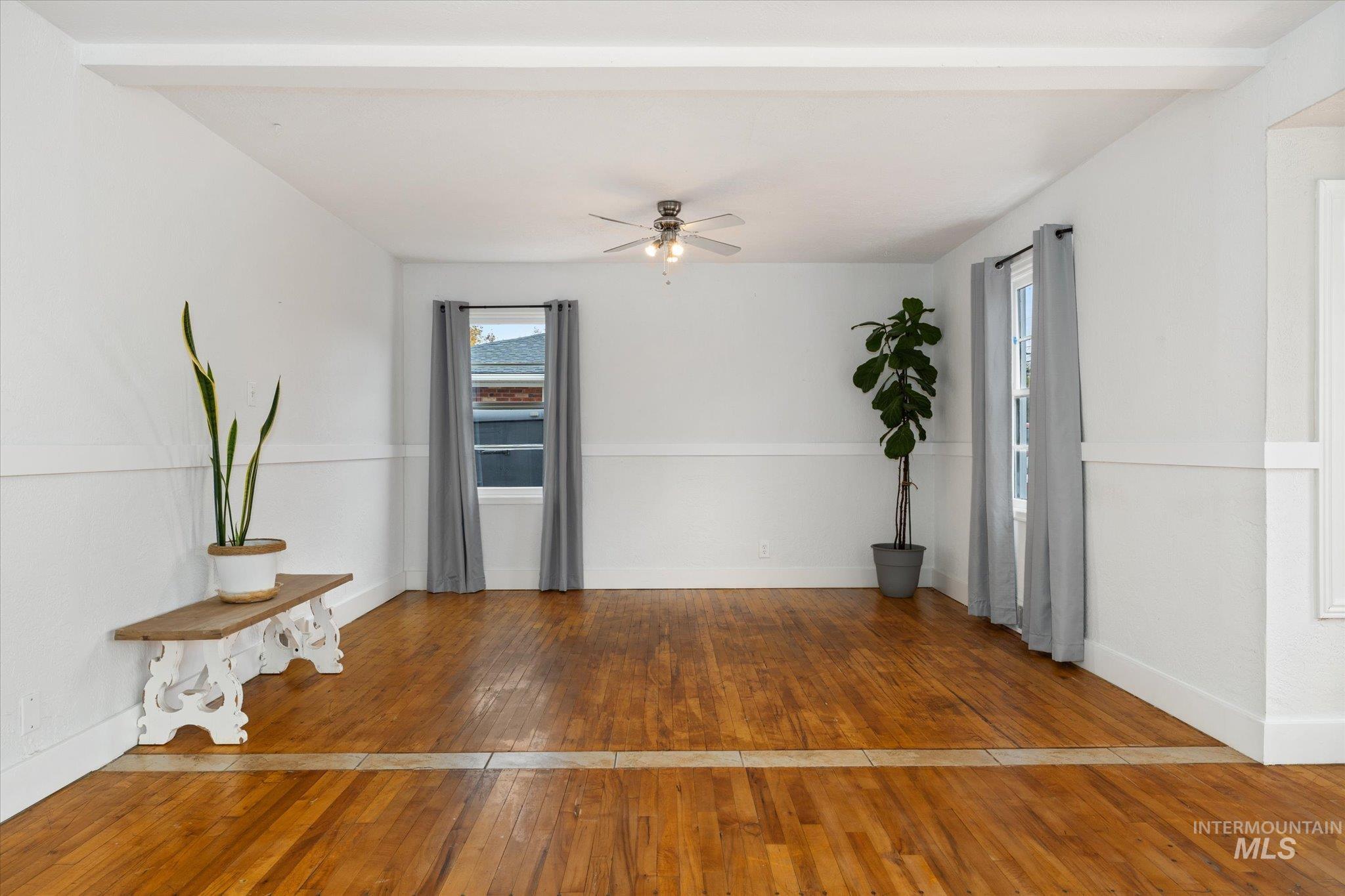 Spare room featuring hardwood / wood-style floors, ceiling fan, and beam ceiling