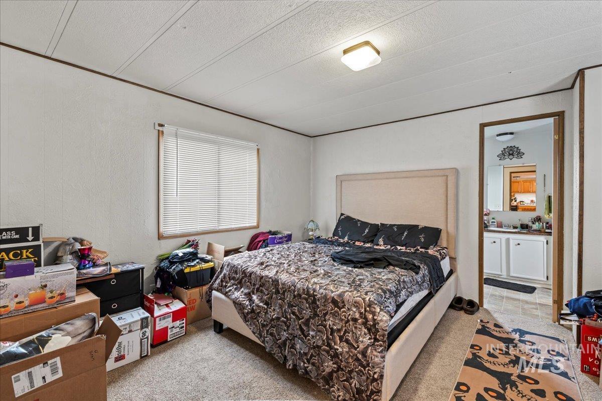 Bedroom featuring light colored carpet, a textured wall, and a textured ceiling
