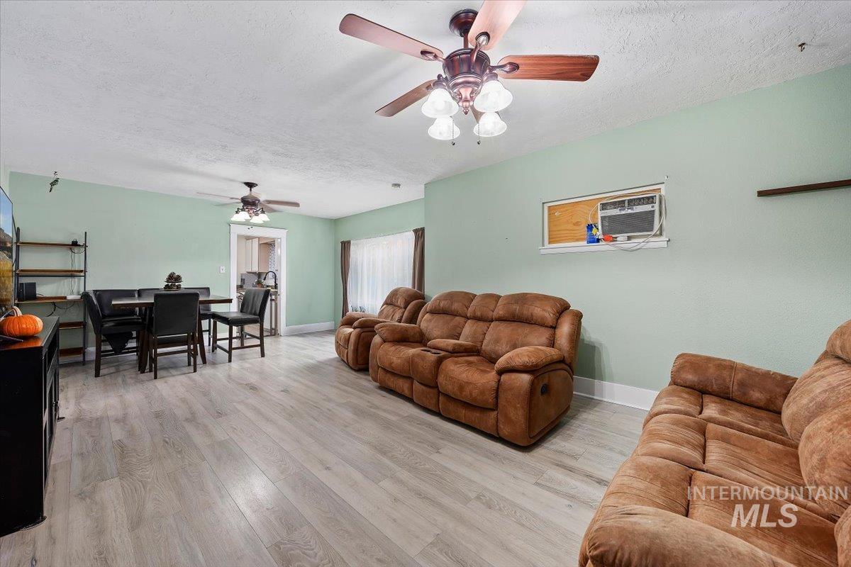 Living room featuring a textured ceiling, light wood-style floors, and ceiling fan