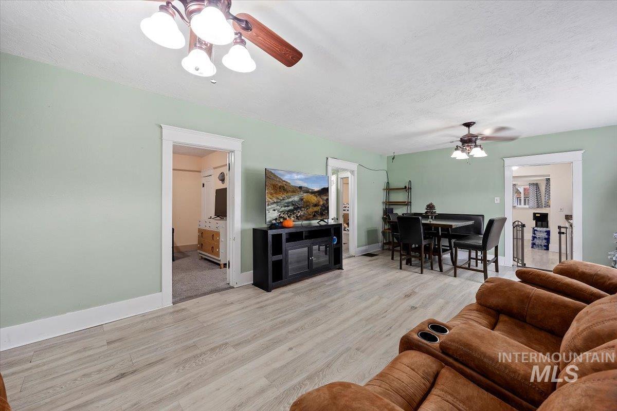 Living room featuring ceiling fan, light wood-style flooring, and a textured ceiling
