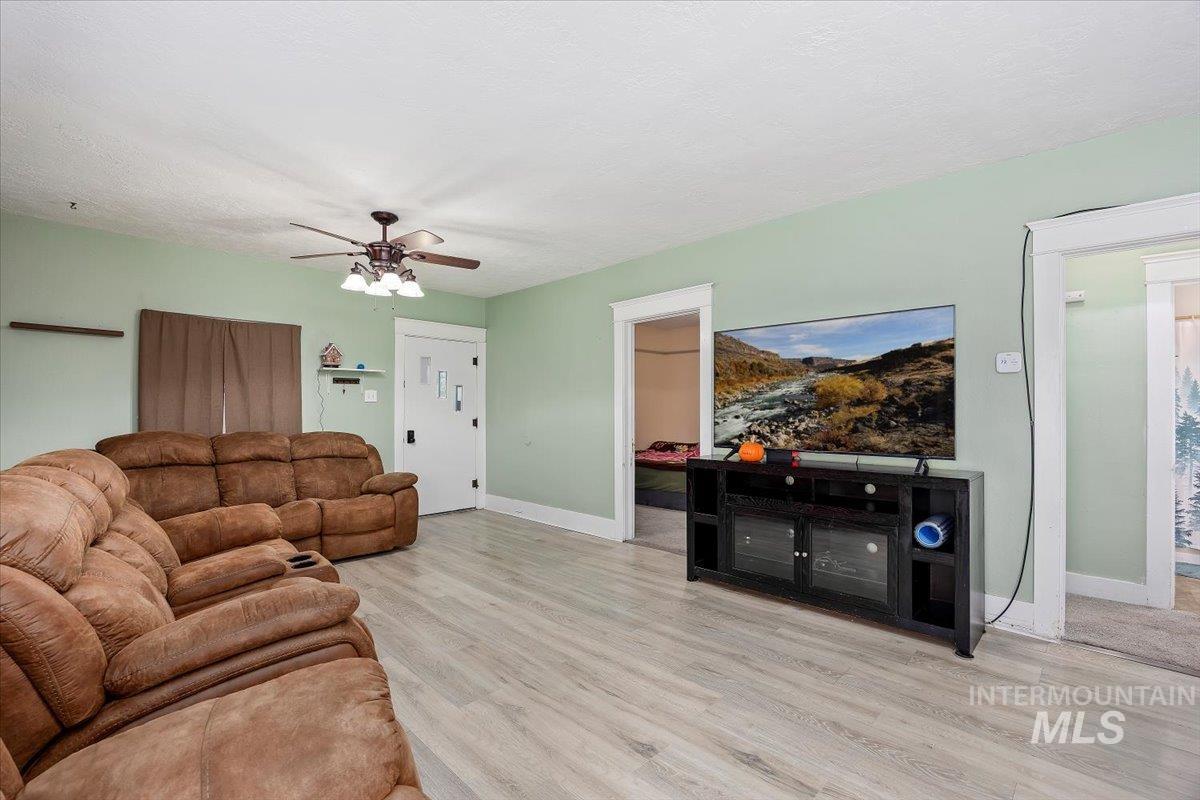 Living room featuring light wood-style floors, a ceiling fan, and a textured ceiling