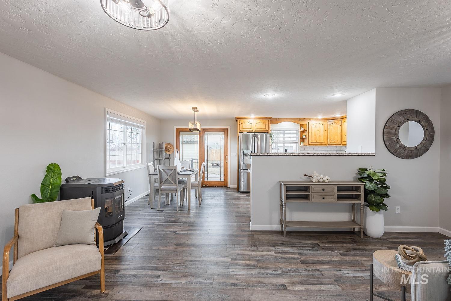 Living area featuring a wood stove, dark wood-style flooring, and a textured ceiling
